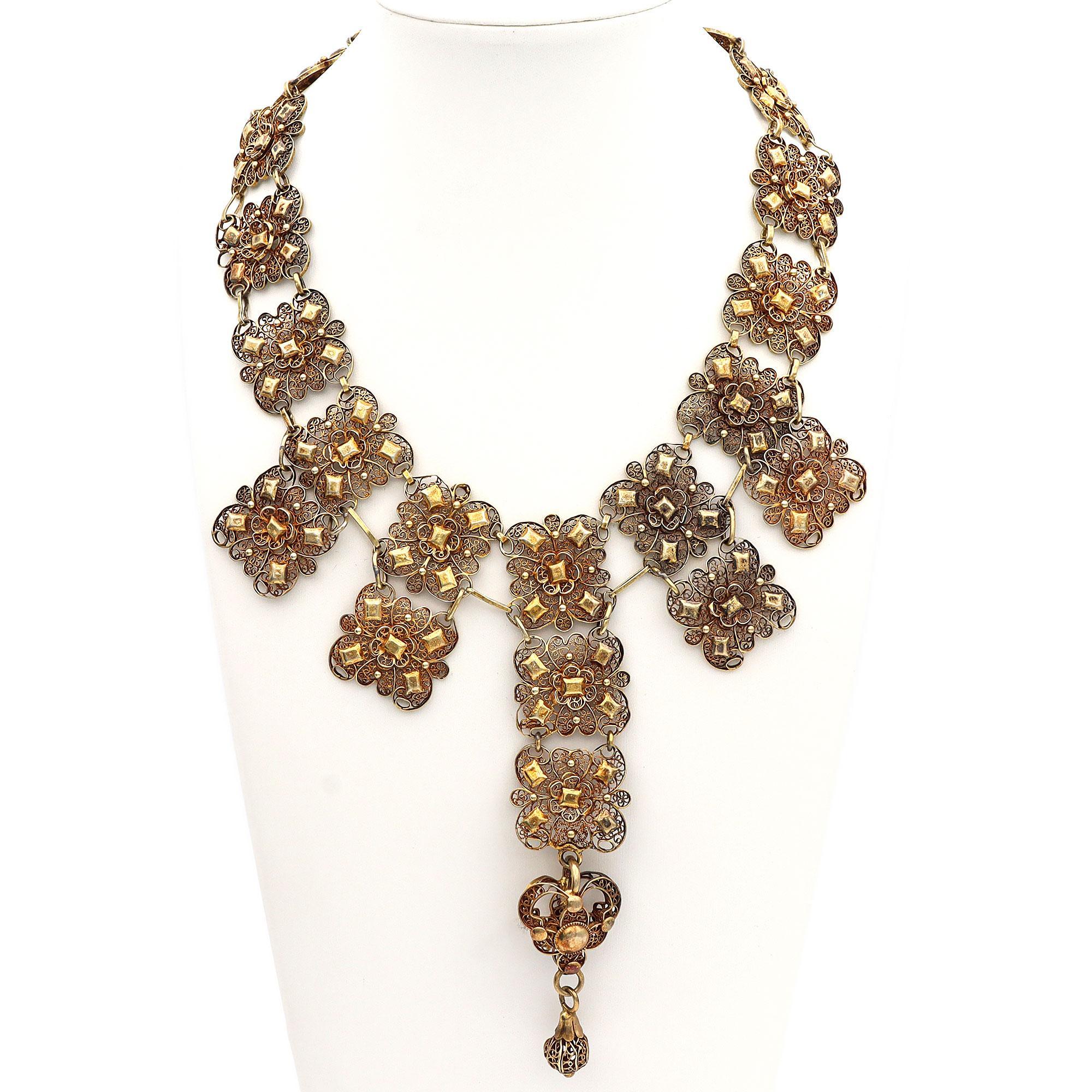 Una splendida parure di gioielli in vermeil. Il set comprende una collana e un braccialetto, ognuno dei quali presenta intricati motivi floreali. Il design presenta una serie di motivi floreali ornati e intrecciati che creano un aspetto armonioso ed
