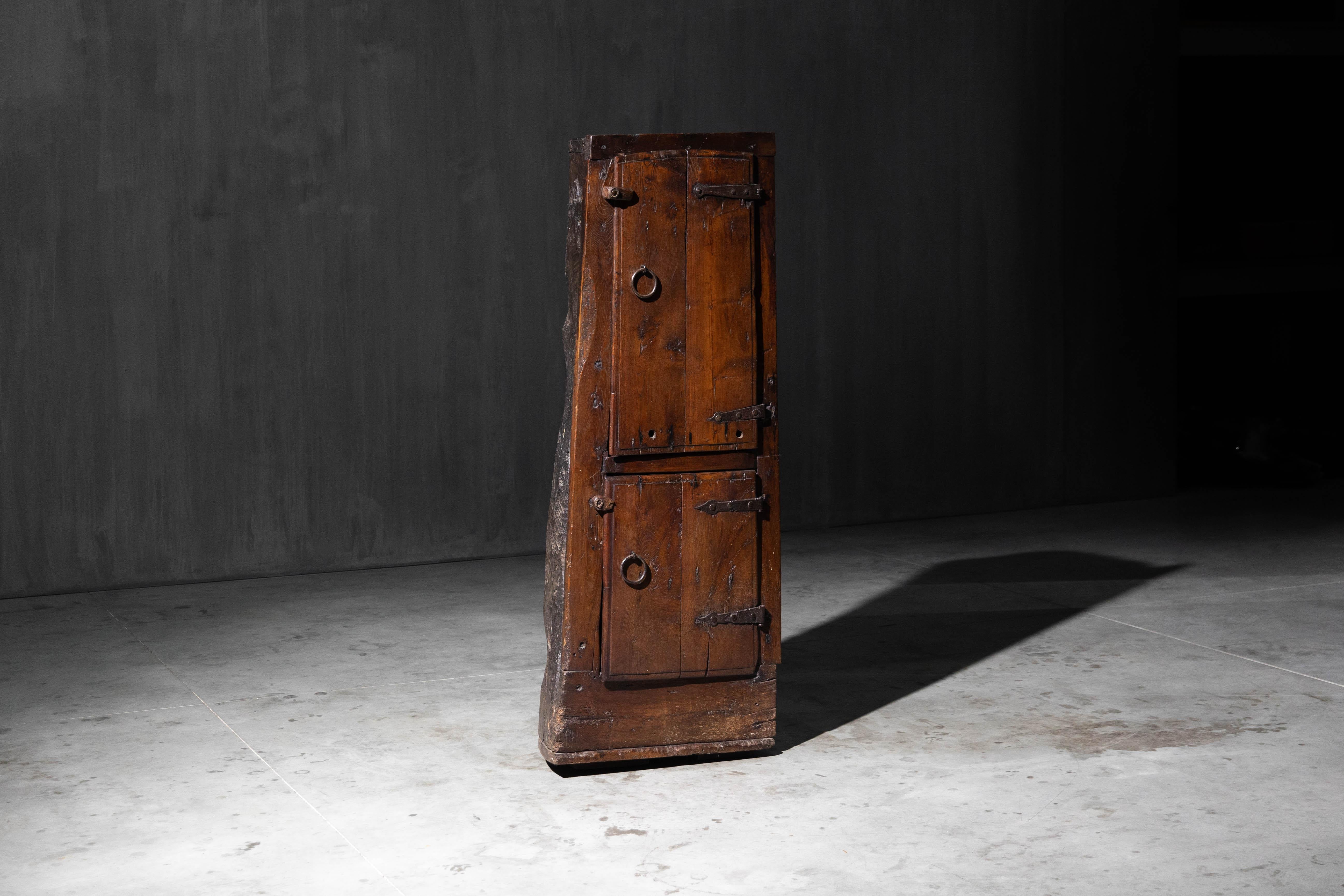 Questo autentico mobile wabi-sabi mostra la bellezza dell'imperfezione e dell'artigianato consumato dal tempo. Scolpito a mano da un unico pezzo di legno massiccio, presenta bordi naturalmente irregolari, patina invecchiata e ferramenta in ferro