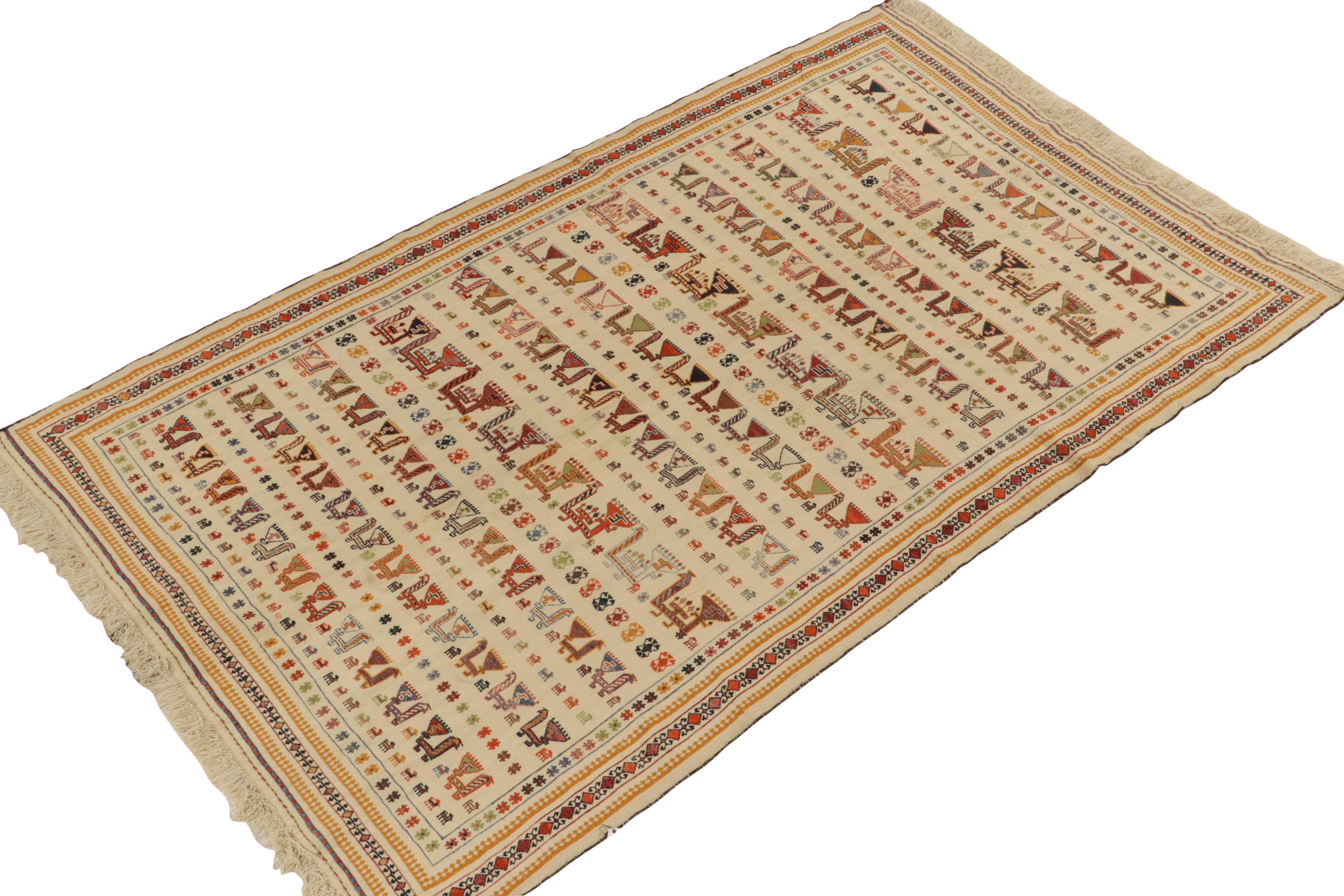 Handwoven in wool circa 1920-1930, a 5x8 antique Verneh kilim rug among our most coveted curations of masterful Persian rugs. 

The colorful piece enjoys meticulously detailed motifs in rows that grab the eye against the forgiving, cool beige