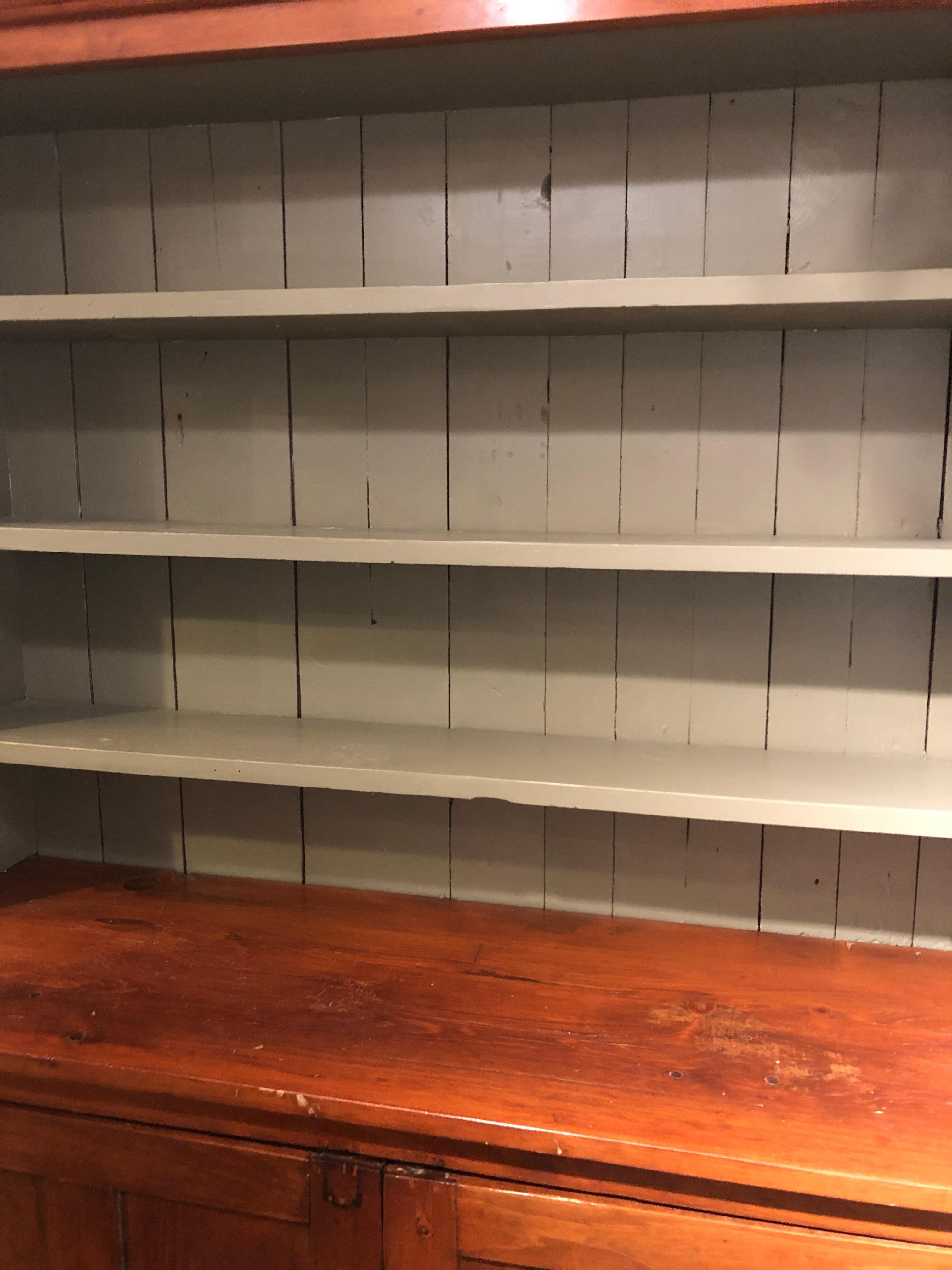 A very large 19th century cupboard cabinet made of pine and poplar with a cherry colored finish and pale blue painted interior shelves. The two panel doors below open to more storage inside. Shelves are 8 D, top surface above doors is 18 D body is