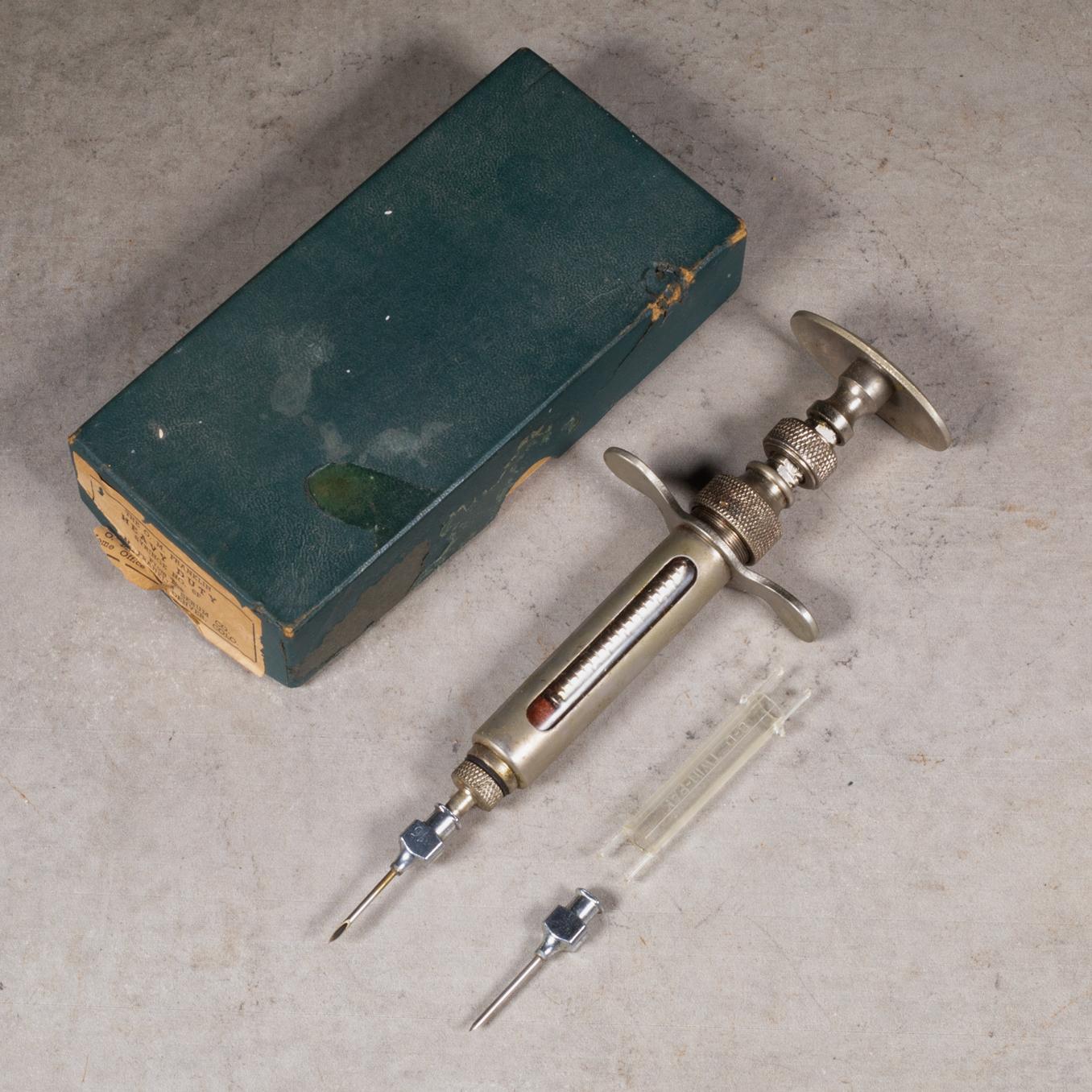 CIRCA

Antica siringa per siero veterinario in metallo con due attacchi per l'ago e scatola ed etichetta originali. Inciso su entrambi i lati. 

    CREATORE A&M. Franklin Serum Company. 
    DATA DI FABBRICAZIONE 1930 circa.
    MATERIALI E