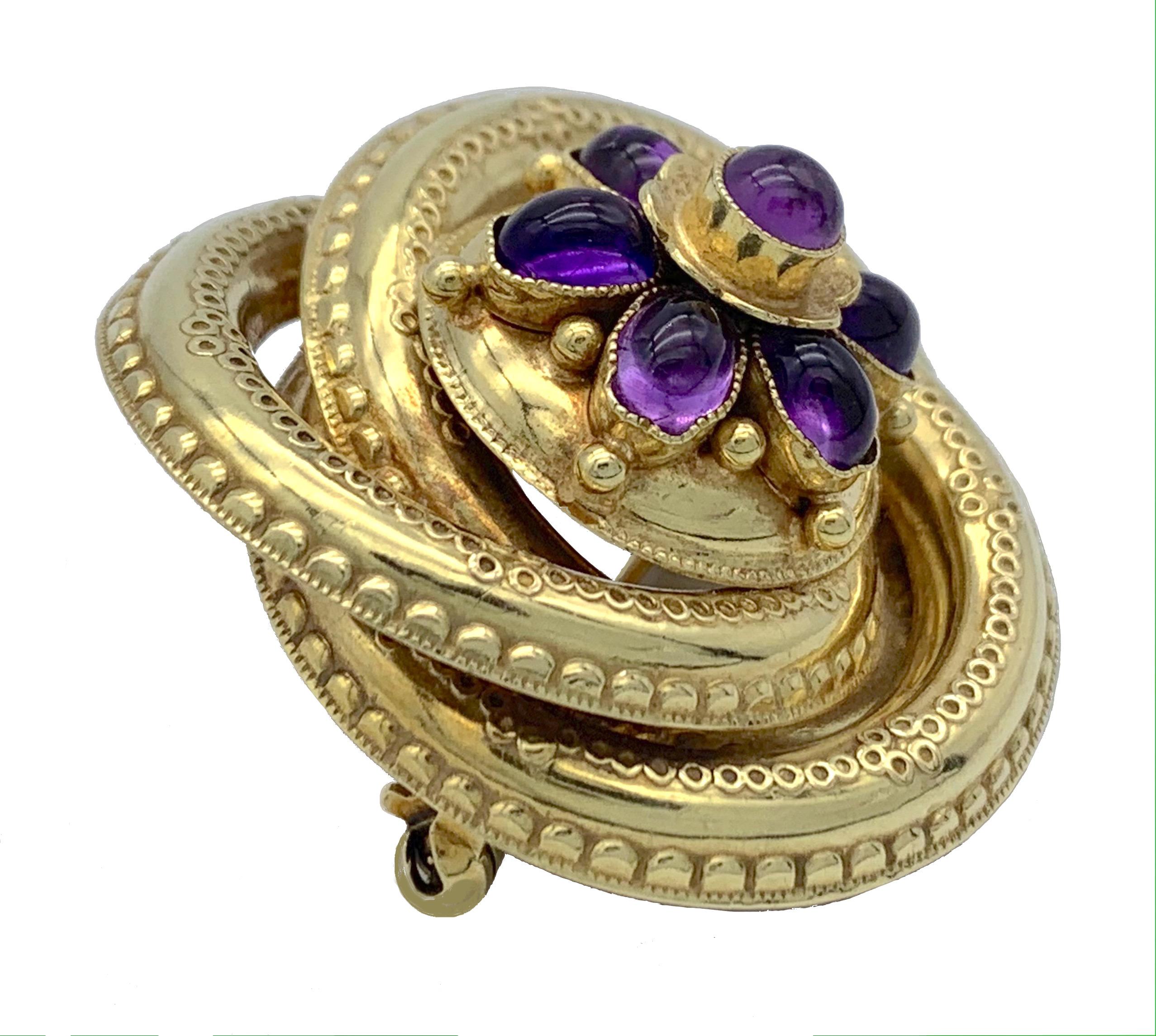 This striking victorian brooch is designd as an entwined eternity knot. The centre of the brooch is decorated with a large flower. Seven flower petals are set with oval cut amethyst cabochons. The centre of the flower is set with a round cut