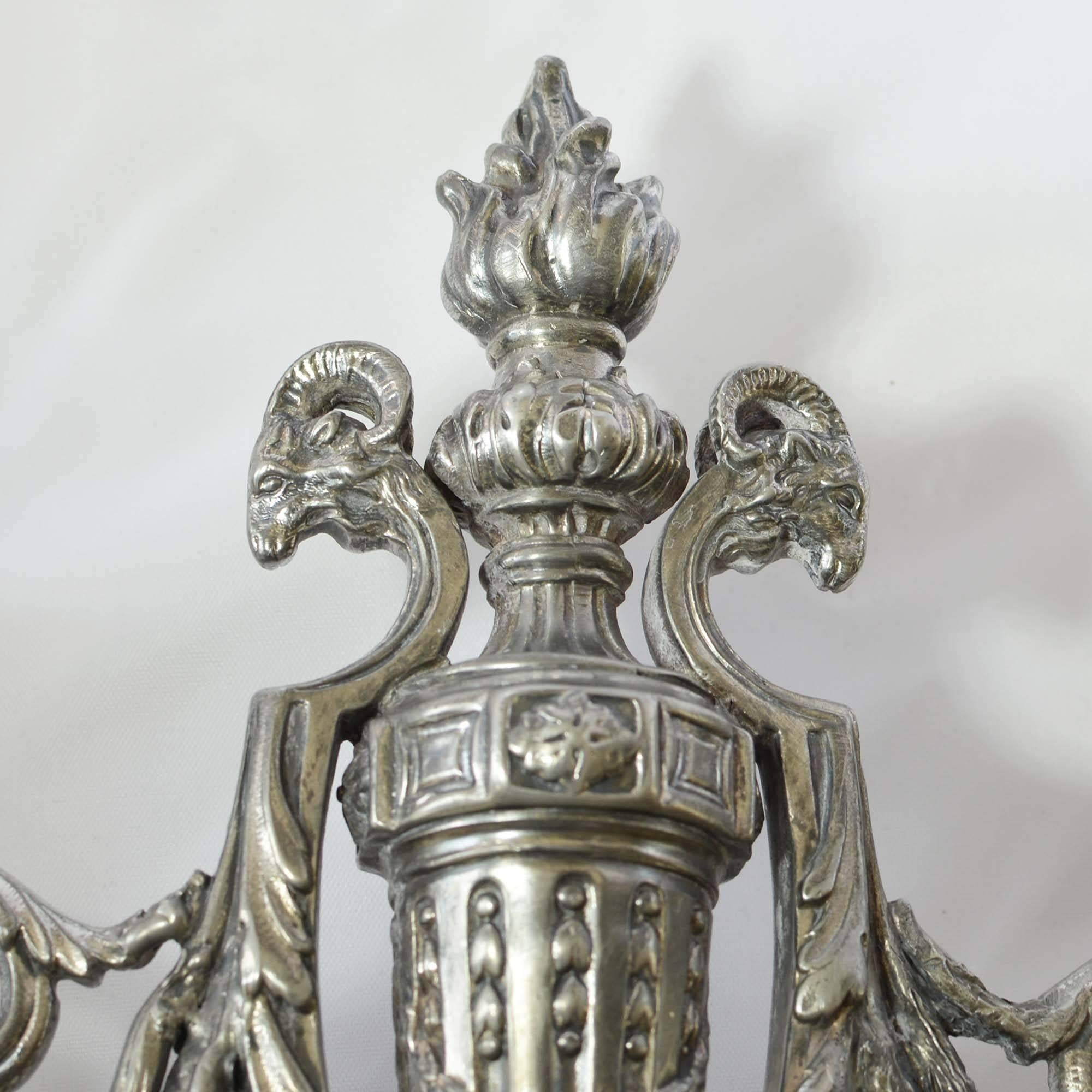 A pair of late 19th century silver plate candelabras by Victor Saglier of Paris, France. The pair of candelabras are beautifully detailed in design. These matching Art Nouveau candelabras feature figural flame finials, ram’s head accents on their