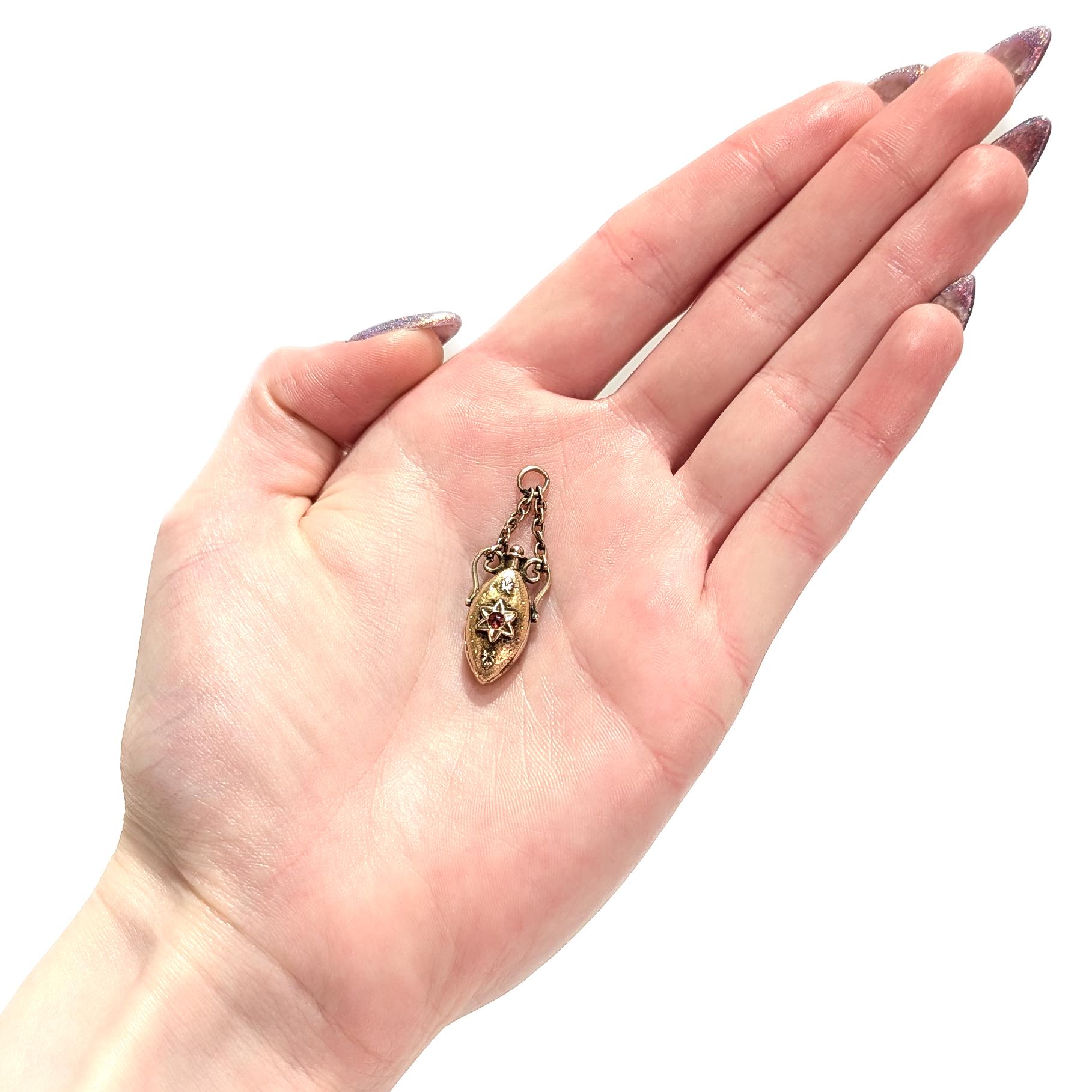 Ein schöner antiker viktorianischer Charme für ein Armband.

Aus 10 Karat Gelbgold mit silbernen Akzenten.

Die amphorenförmige Miniaturflasche (nicht funktionsfähig) mit einer Sternkartusche in der Mitte eines facettierten Glassteins.

Gestützt