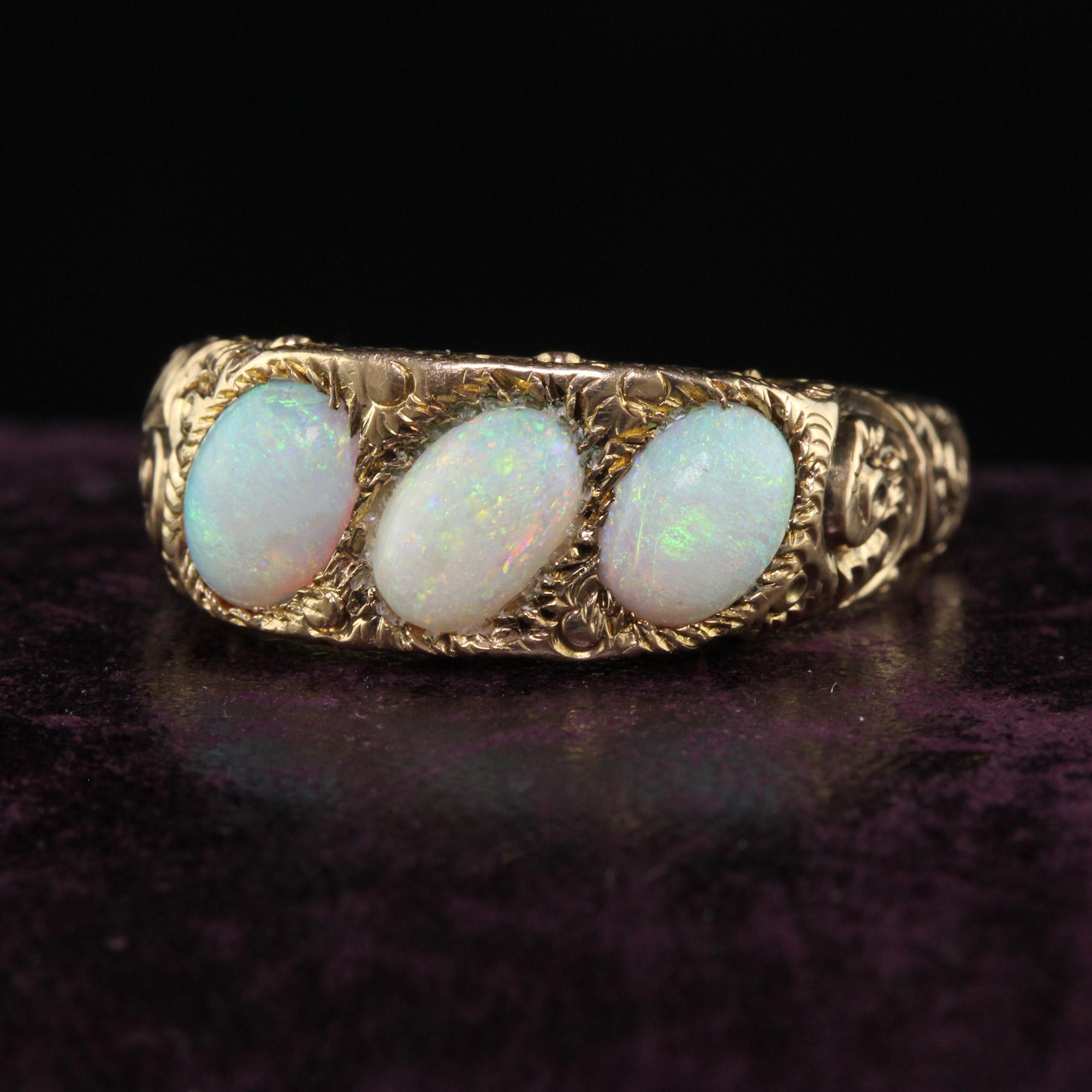 Beautiful Antique Victorian 12K Yellow Gold Three Stone Opal Engraved Cocktail Ring. This beautiful three stone band is crafted in 12k yellow gold. The center holds three oval cut opals that are set at an angle which is very unique. The sides are