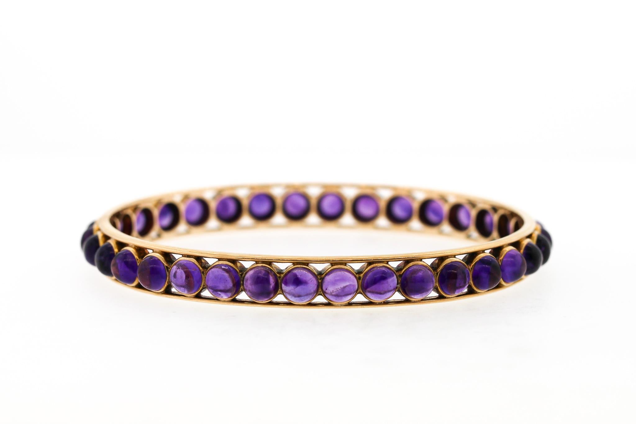 Unusual and easy to wear, this antique Victorian gold bangle set with cabochon amethysts is attractive and versatile. The concentric amethysts set all the way around the oval bangle is unusual with such a modern aesthetic. The bracelet is very easy