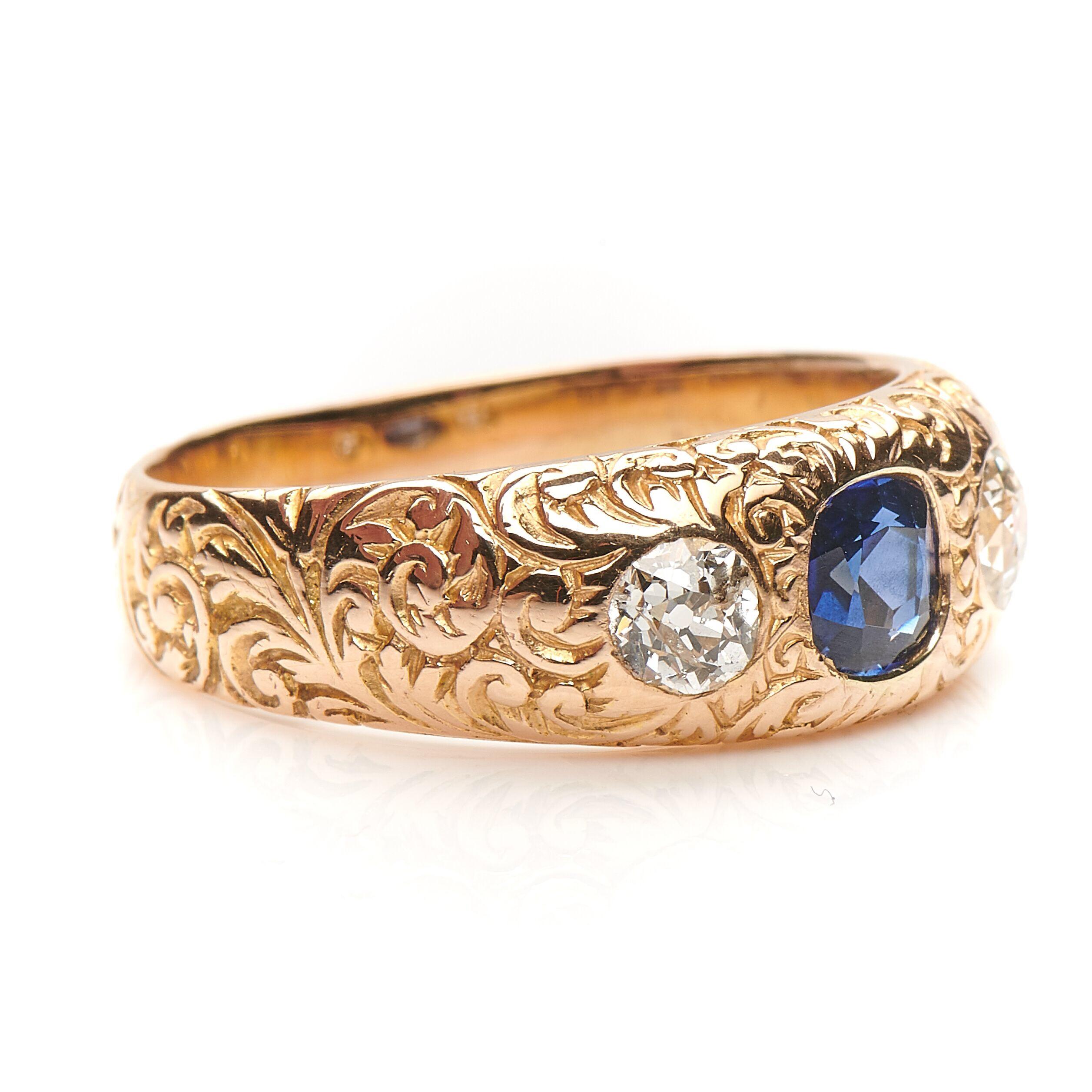 Victorian, sapphire and diamond gypsy ring, circa 1880. Set with a old cushion shape sapphire to centre flanked by two old cut diamonds set in the most beautifully carved gold. The band is ornately carved to the exterior with a repeating pattern of