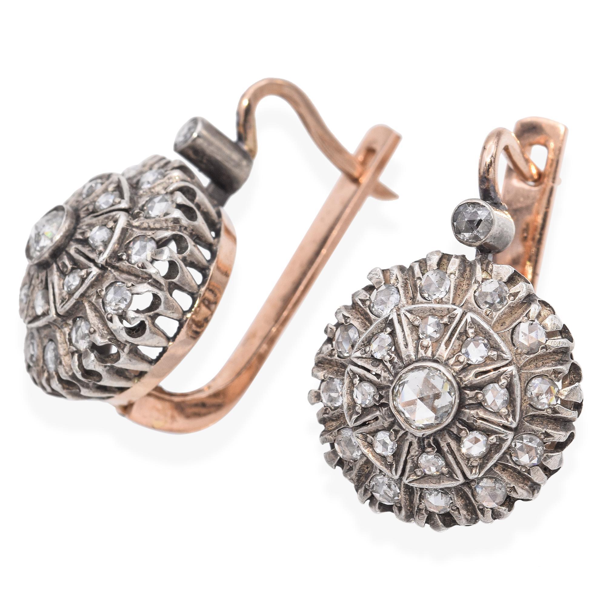 Boucles d'oreilles anciennes présentant des motifs ronds complexes. La montre est ornée d'un arrangement détaillé de petits diamants étincelants de taille rose sertis dans un motif circulaire. La pierre centrale est entourée d'une série de pierres
