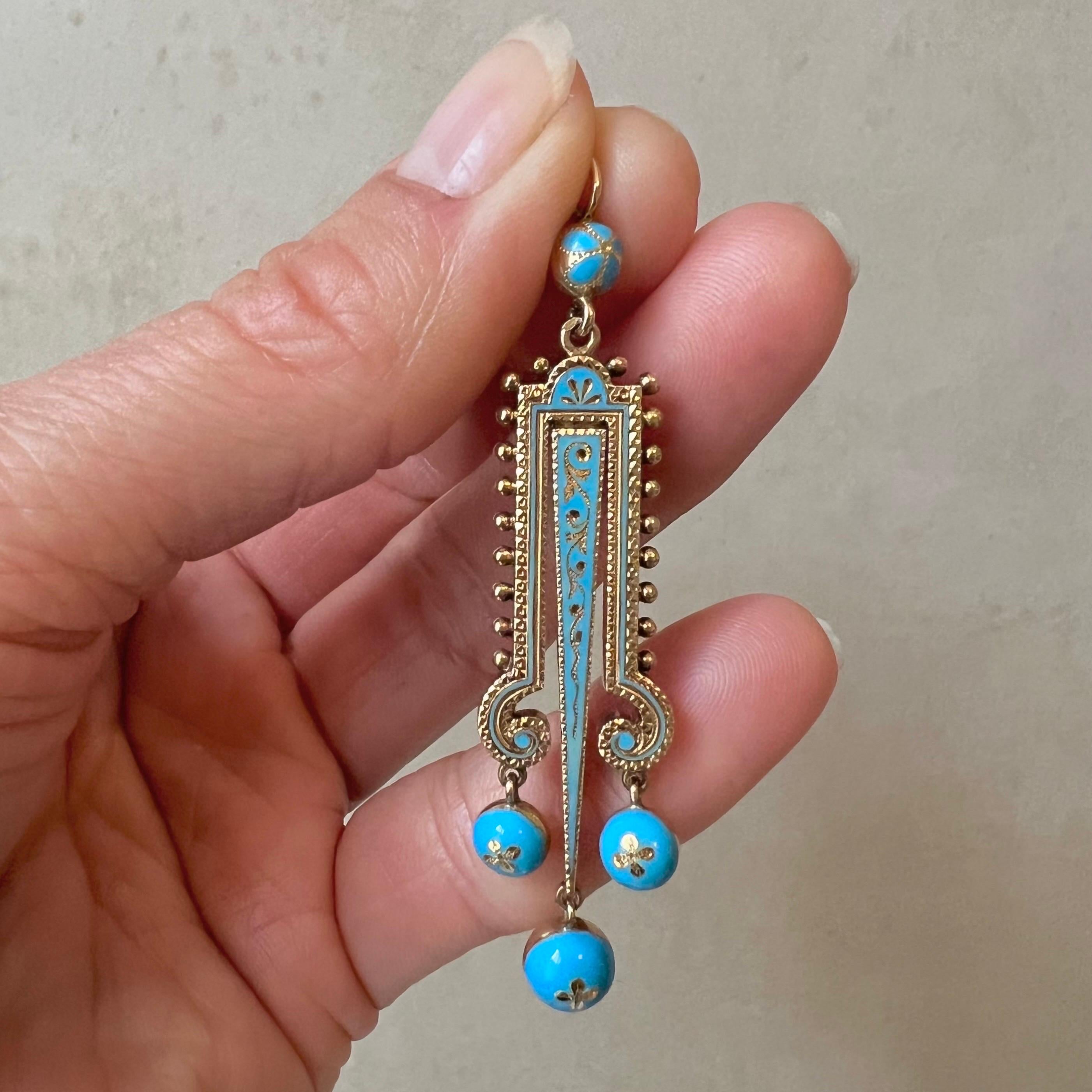 Entra nell'eleganza del passato con questo antico pendente vittoriano in oro 14 carati e turchese smaltato. Il ciondolo è splendidamente incastonato con una fila verticale di piccole sfere d'oro su entrambi i lati, mentre il disegno sul davanti