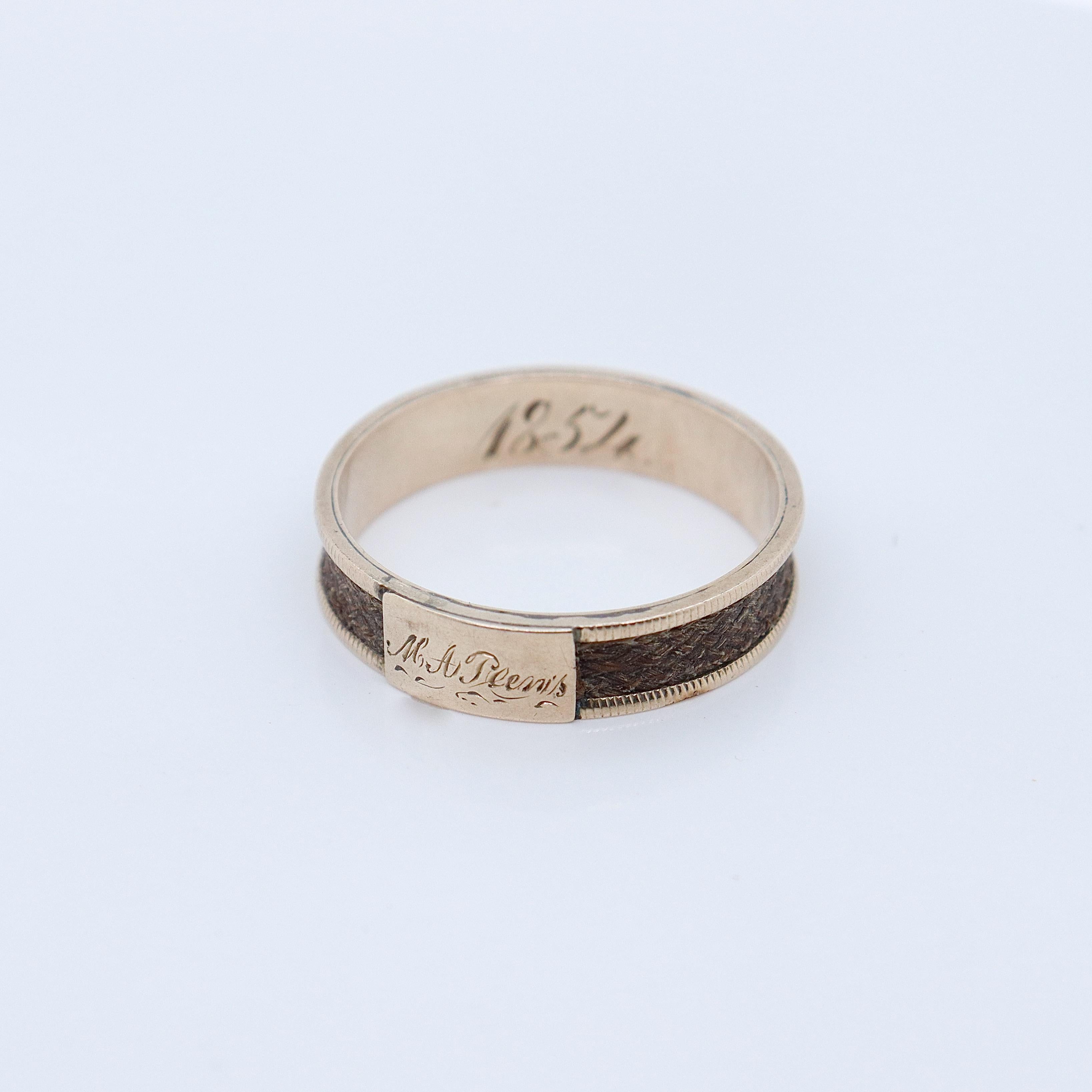 A fine antique Victorian mourning band ring.

In 9k gold.

Channel set with a strand of braided hair. 

Engraved with a name to a plaque on the front and with the date 1854 to the shank.

Simply a wonderful mourning ring!

Date:
1854

Overall