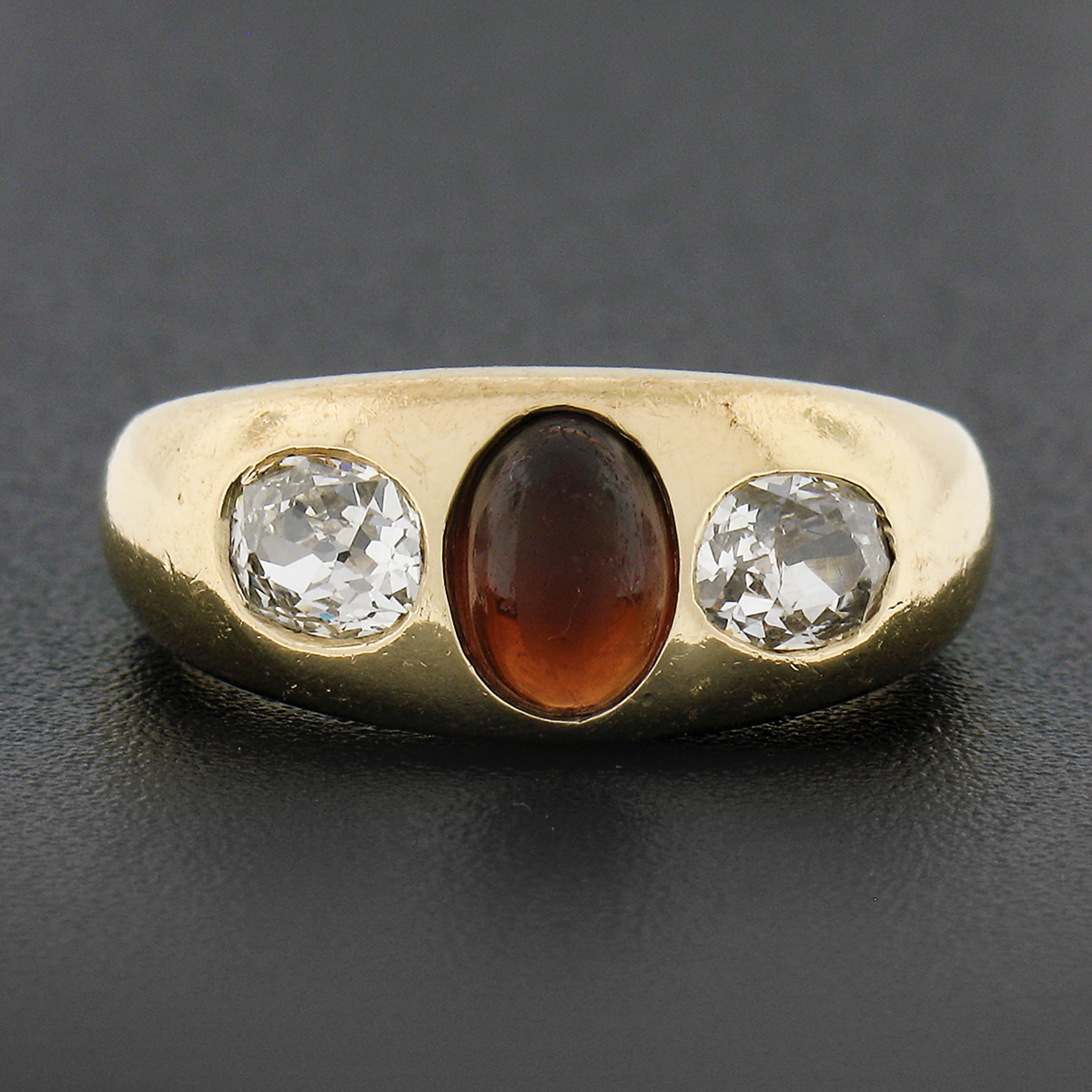 Here we have a beautiful antique ring that was crafted in solid 14k yellow gold during the late Victorian period, and features a classic three stone style with an oval cabochon garnet neatly set at the center. The natural garnet has a rich red color
