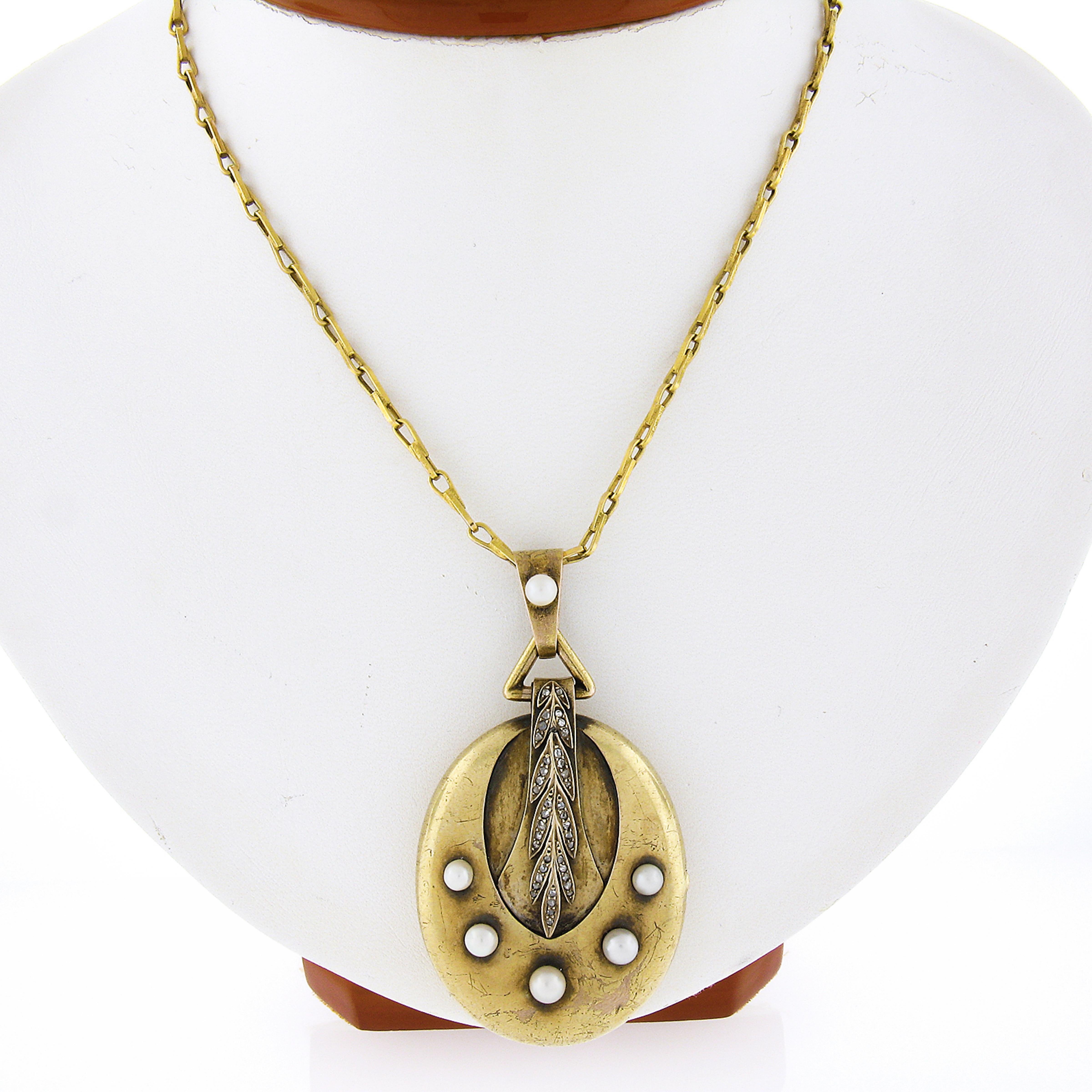 This large and unique antique pendant necklace was crafted in solid 14k yellow gold during the Victorian era and features an oval locket adorned with cultures pearls and numerous old rose cut diamonds pave set in the wonderful wheat designs across
