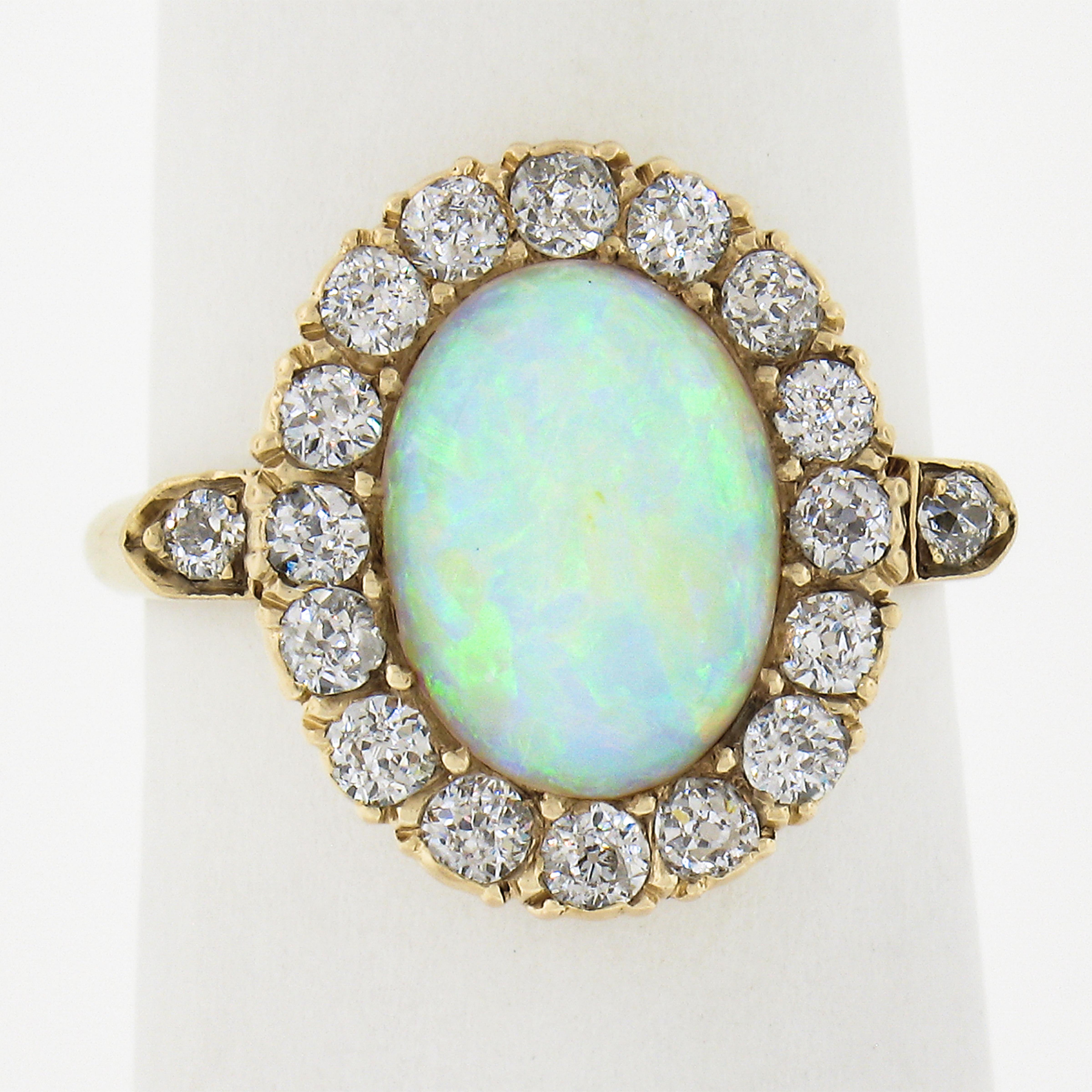 This super cute Victorian era ring is crafted in solid 14k gold and features an oval cabochon opal stone displaying vibrant blue, green and orange play throughout. The opal solitaire is surrounded by a fiery halo made from 16 pave set old European