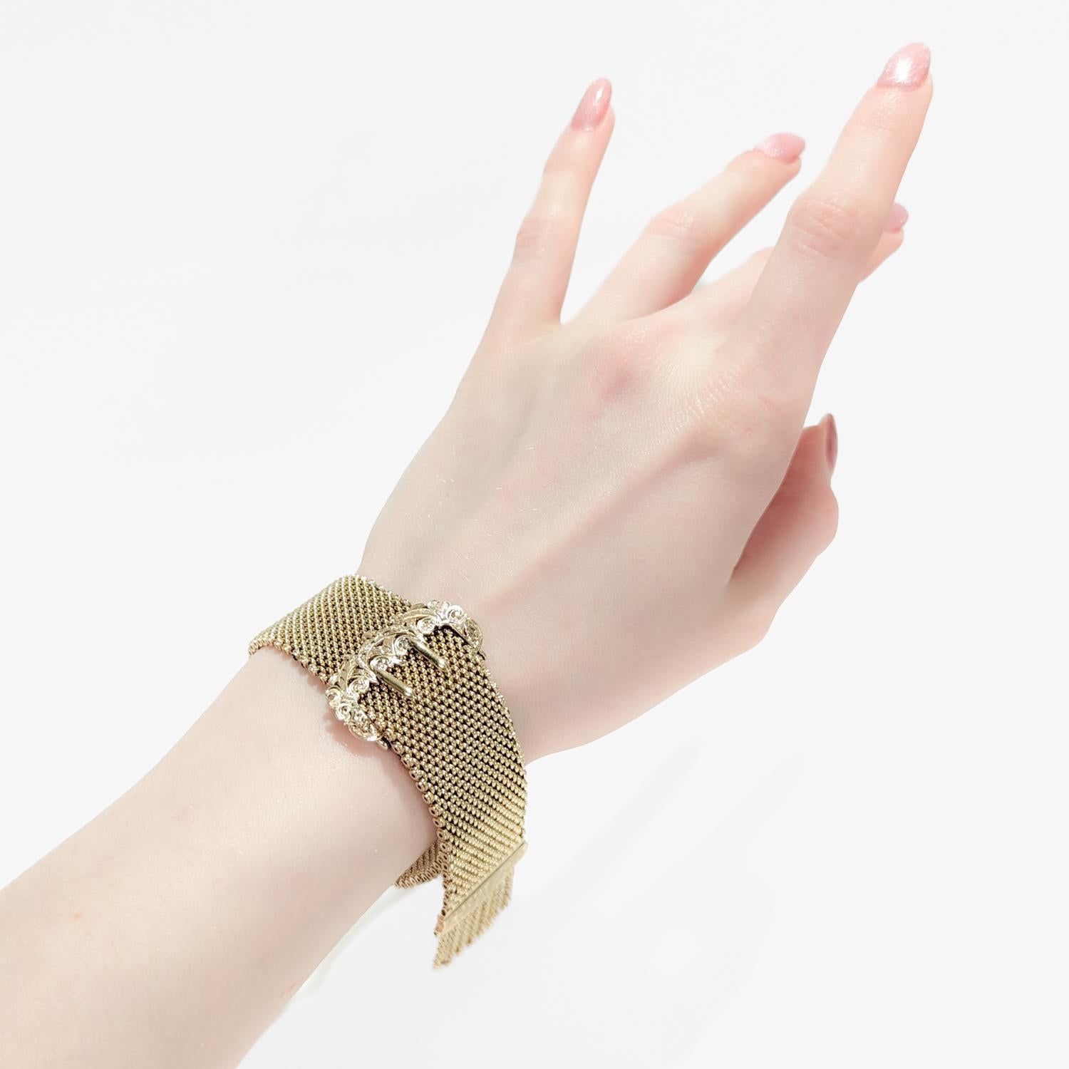 A fine Victorian slide bracelet.

In 14 karat yellow gold (possibly 15k - as some of these were).

Comprising a finely-woven, thick gold mesh band secured with a brite-cut figural buckle shaped clasp and terminating in gold tassels.

With a nice