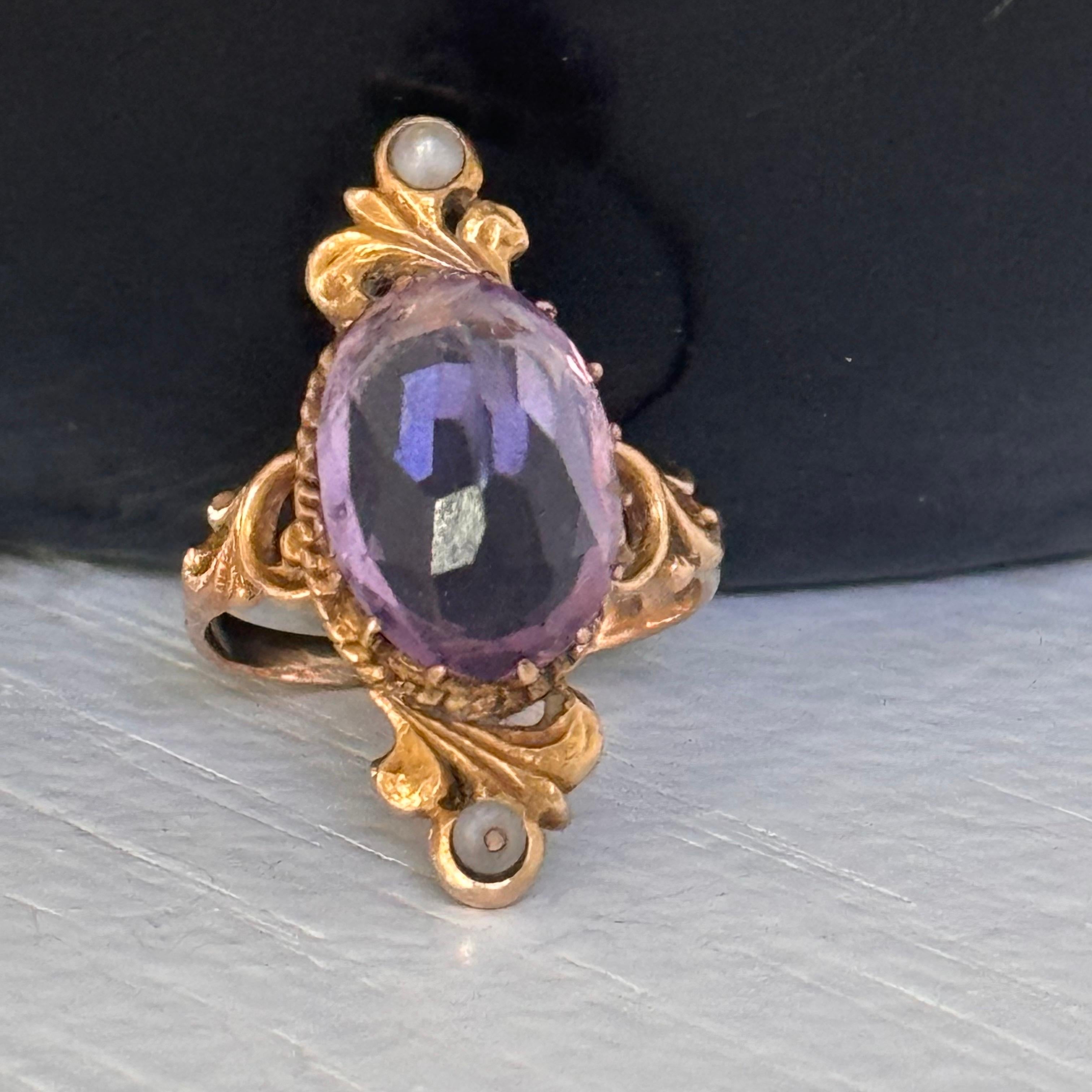 Exquisite Victorian-era ring features a beautifully faceted, central large highly faceted  amethyst set in an ornate prong setting with small seed pearl on two sides . The open-back design allows light to pass through the gem, showcasing its full