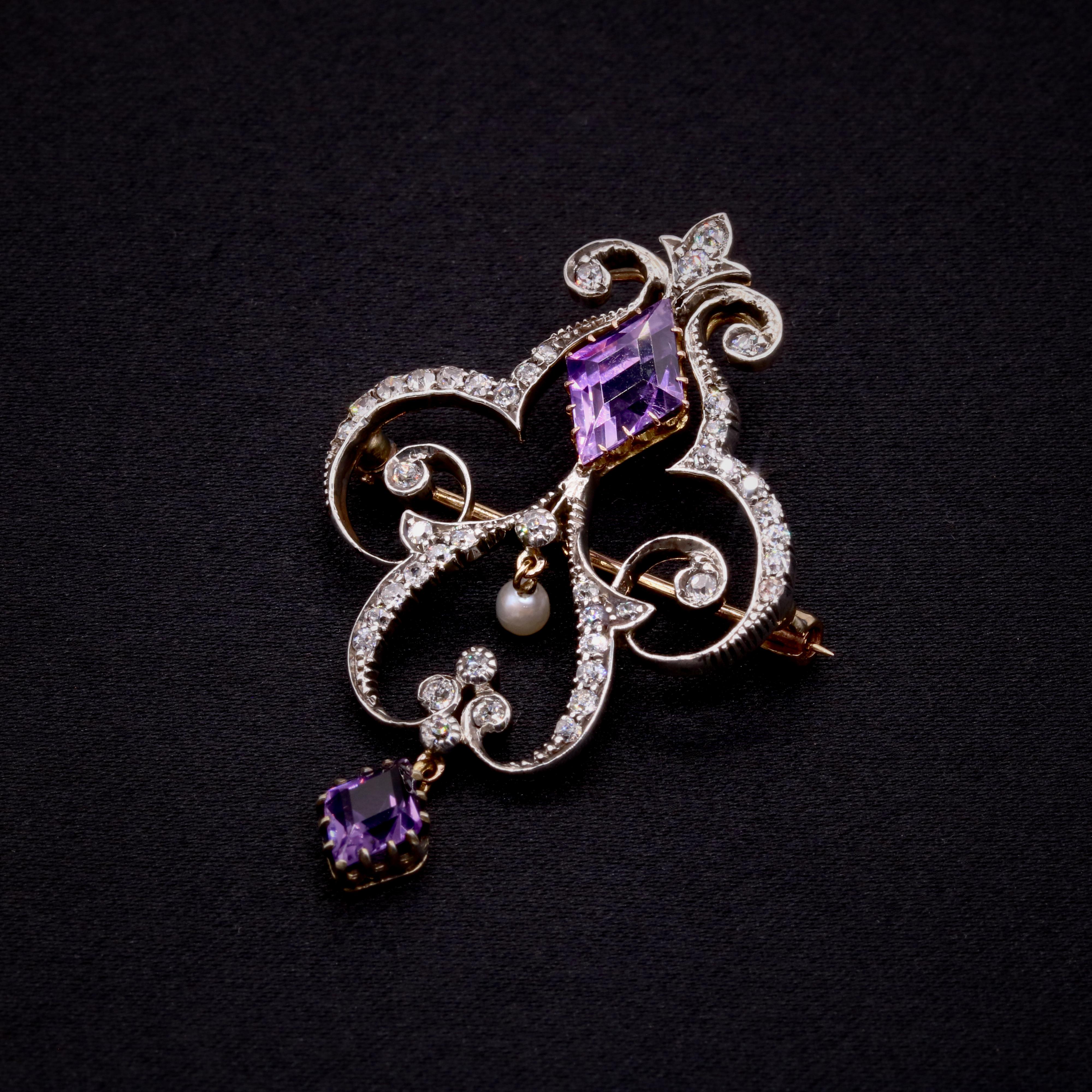 A late Victorian / early Edwardian diamond, amethyst, pearl, yellow gold and silver pendant or brooch, comprising two rhombus shaped amethysts, forty-three old cut diamonds, and one pearl, in 15 karat yellow gold and silver. 

This late Victorian /