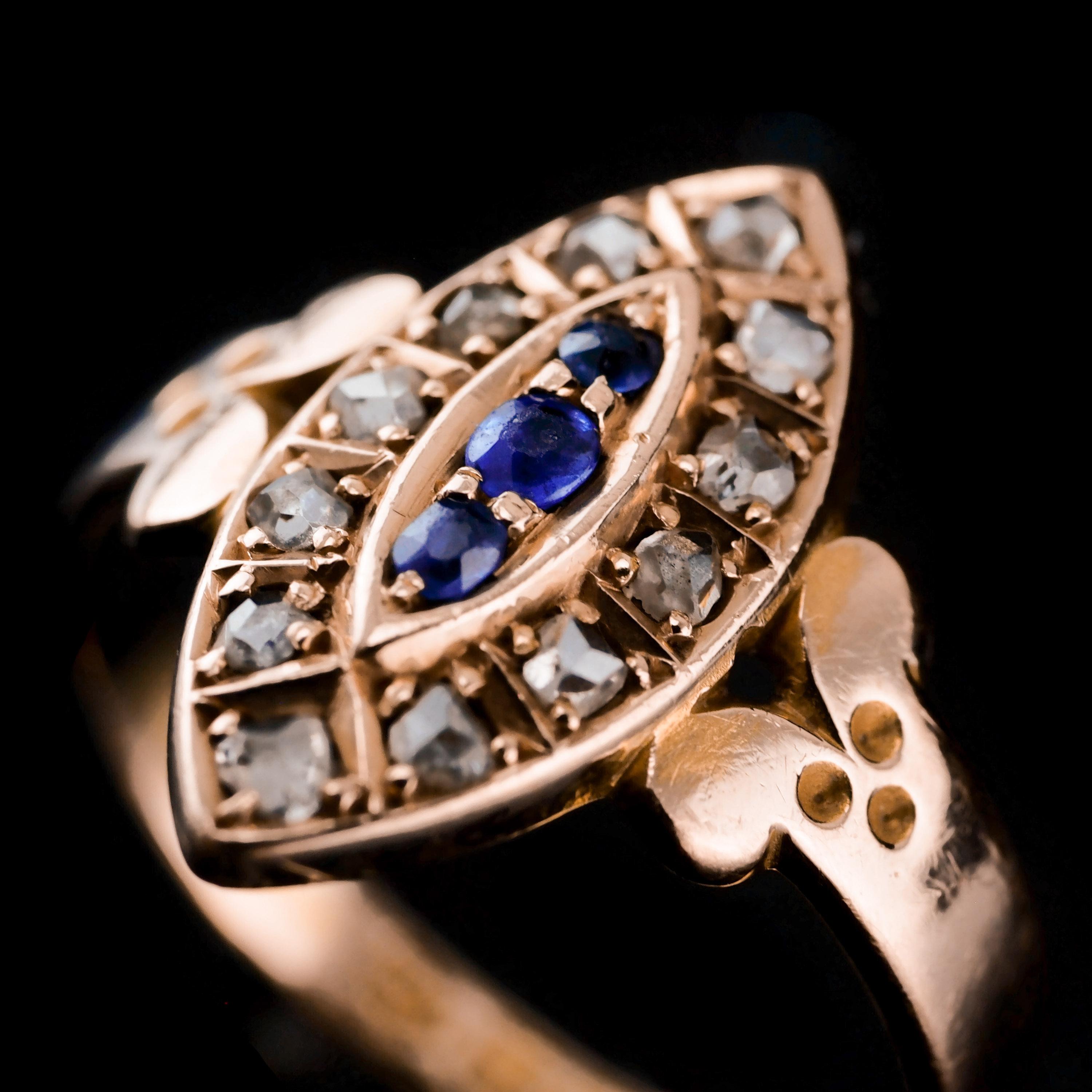 We are delighted to offer this stylish Victorian 15K gold antique navette ring made in Chester 1893.

The ring is beautifully formed in a navette design with the central cluster presenting 3 sapphires in the middle and 12 old rose-cut diamonds on