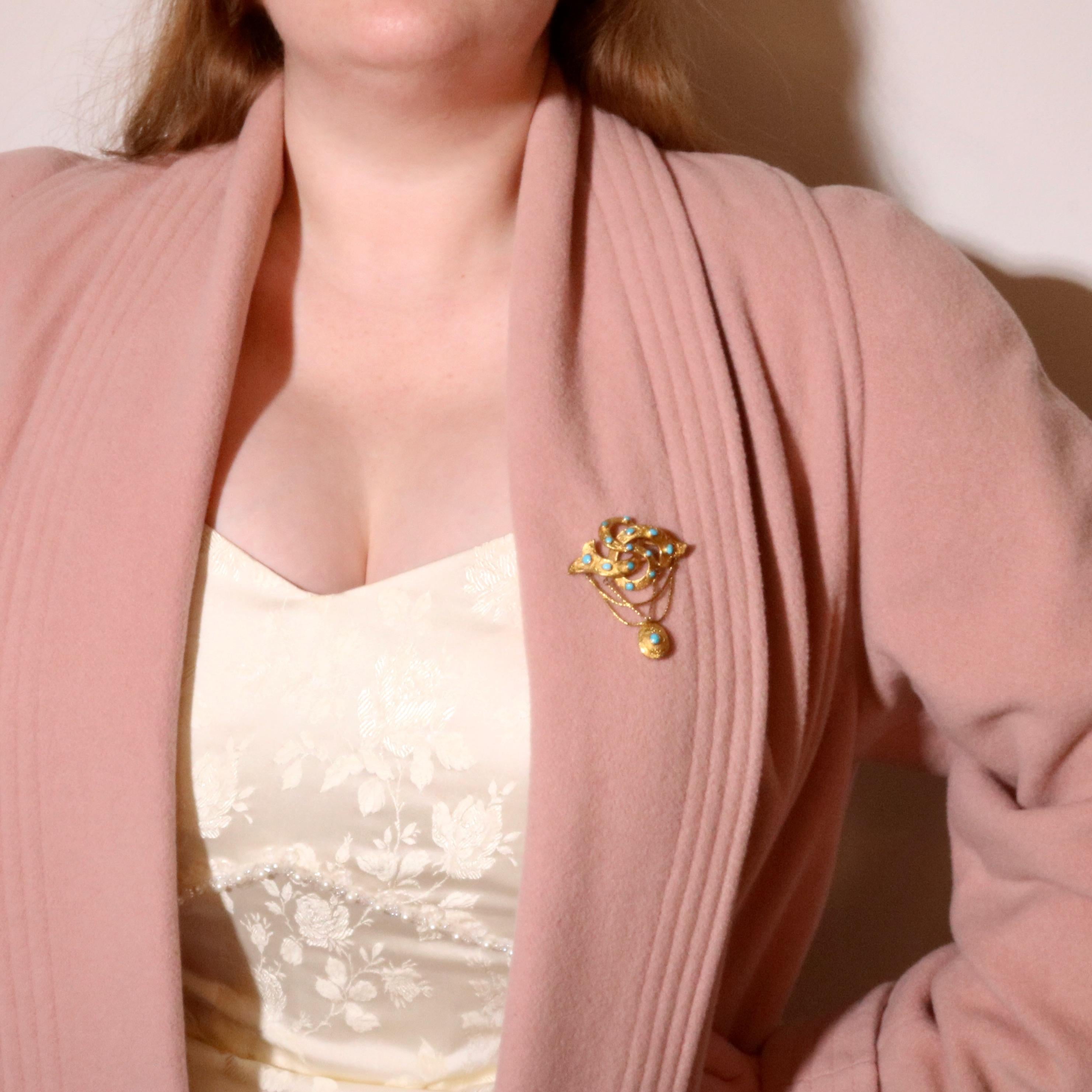 A yellow gold and turquoise brooch, comprising fourteen turquoise cabochons, set in 15 karat yellow gold, with three swagged lengths of chain and a locket compartment, and fittings in 15 karat yellow gold.  

This stunning brooch is beautiful in its