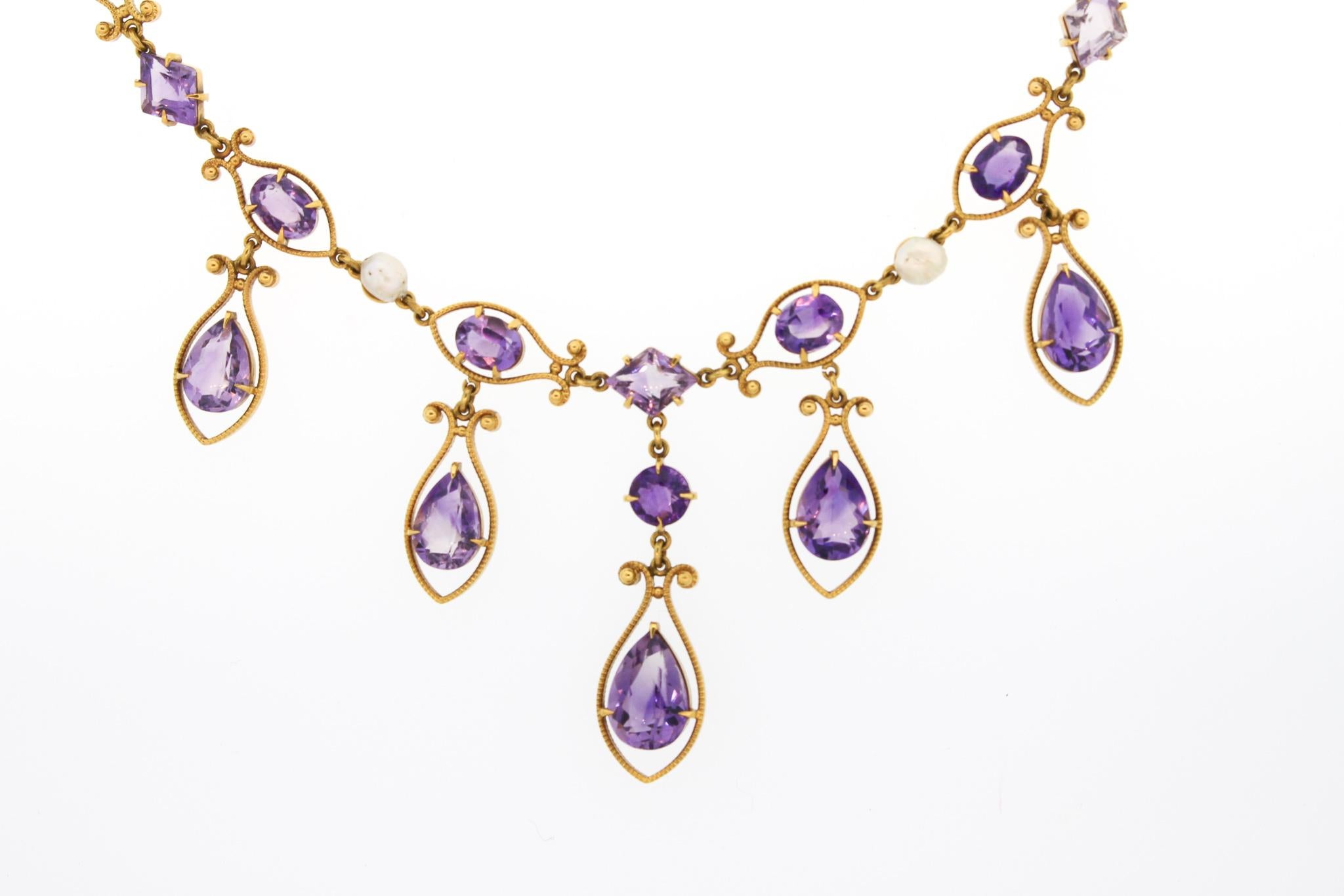A simply charming and unusual 18k gold amethyst fringe necklace with pearl accents from the Victorian era. The necklace dates to about 1880. The necklace is comprised of oval cut amethysts set within milgrain gold wire links, dotted with natural