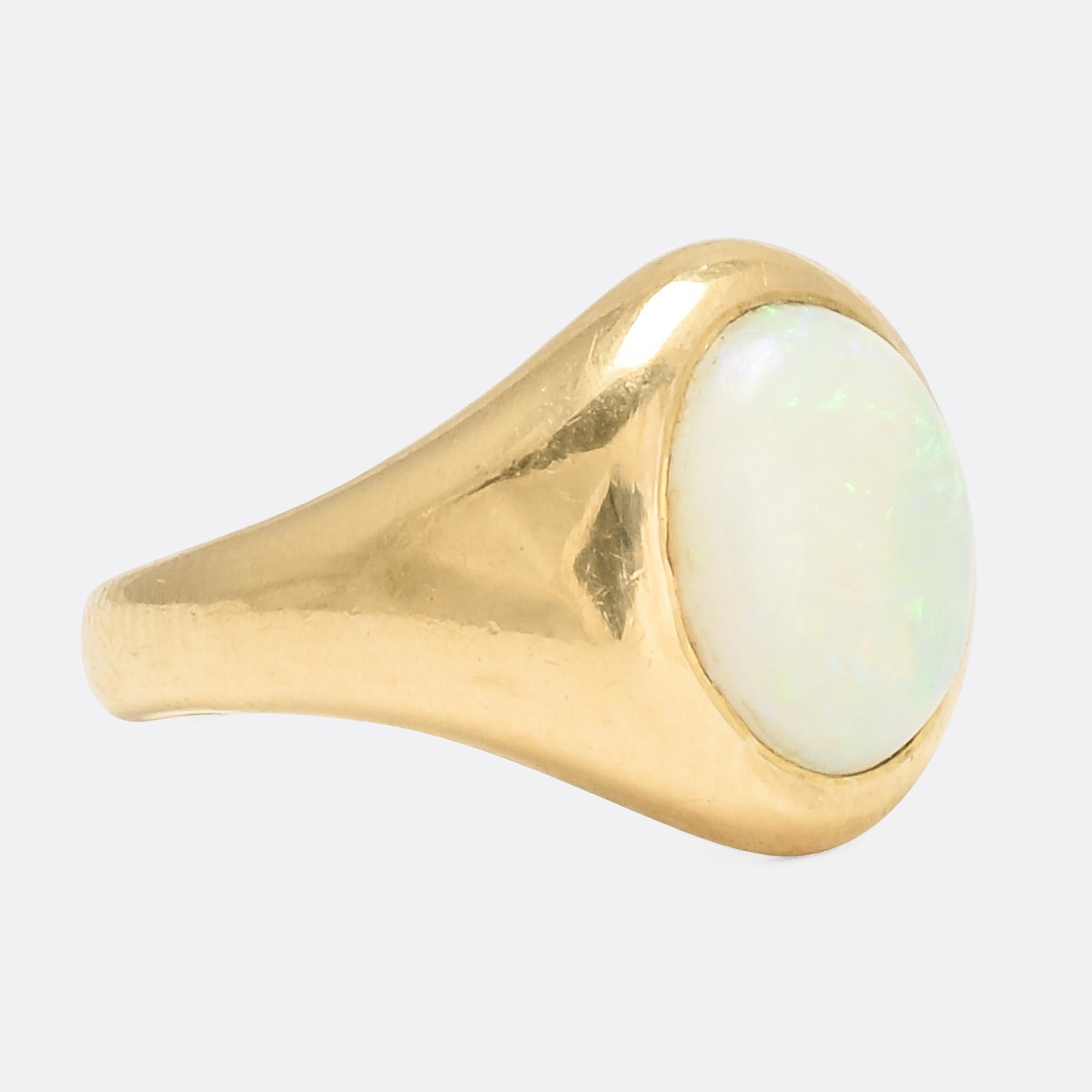 A cool antique signet ring set with a lively opal cabochon. It's crafted in 18 karat yellow gold, with English hallmarks, and dates from the turn of the 20th Century. With a good substantial feel and classic design it's a timeless piece that looks