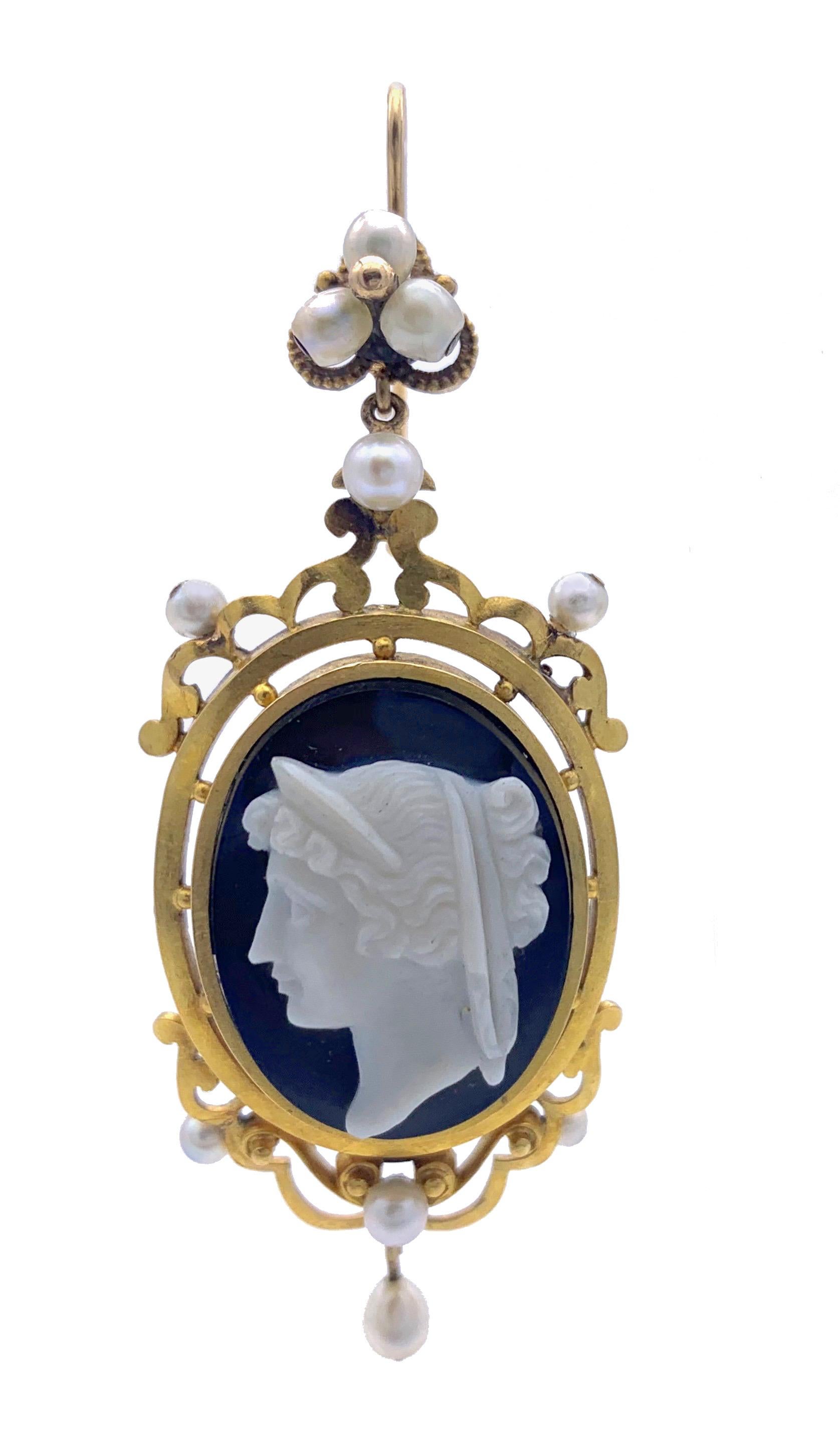 This very elegant and stylish pair of dangling cameo earrings feature portrait busts of elegant ladies in classical ancient hair and headdress carved in 1860 ca. out of black and white layered agate. The 18 carat gold settings are embellished with