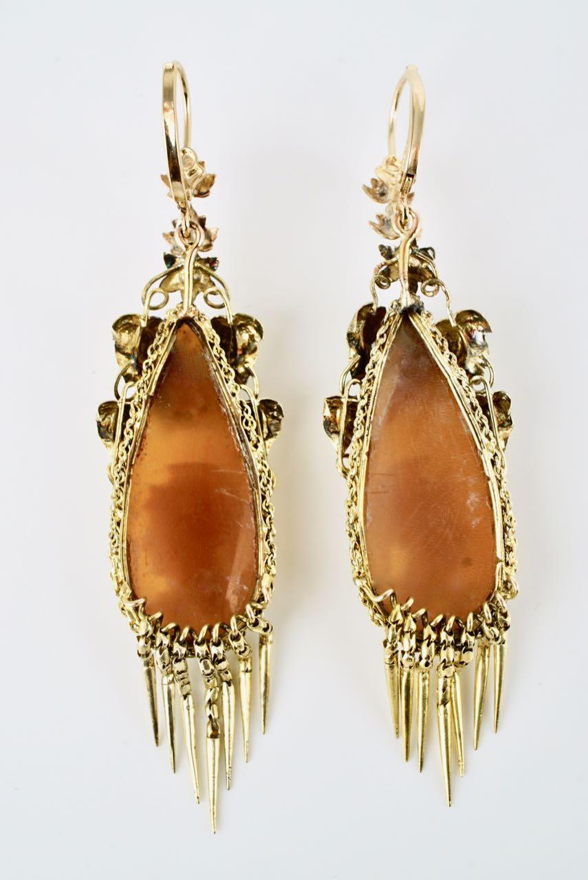 A fine pair of Antique Victorian cameo earrings, each earring consisting of a finely detailed carved drop shaped Conch shell cameo showing the profile of Athena below a floral motif, bezel set within an 18k yellow gold mount of a border of finely