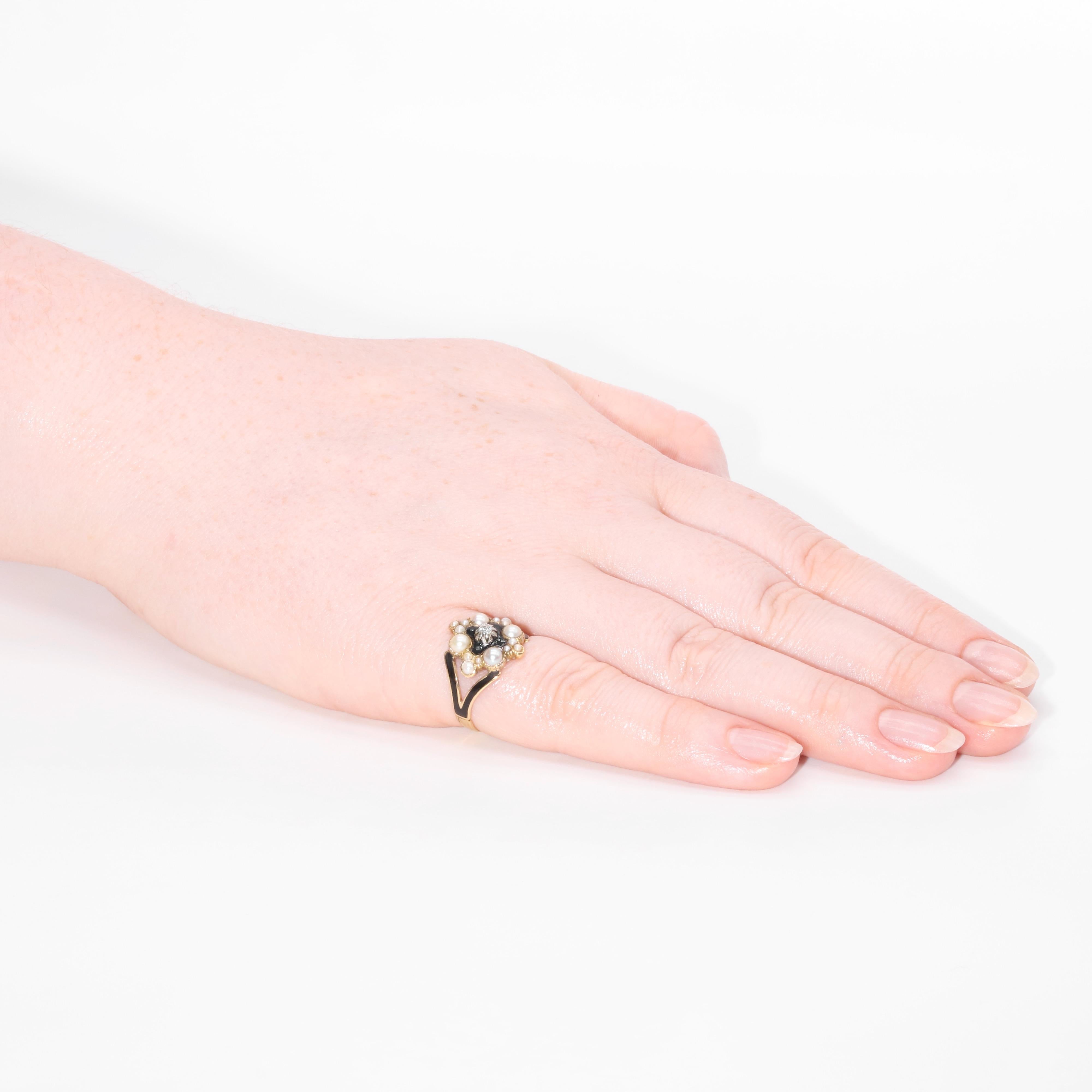 An antique yellow gold, pearl, black enamel and diamond ring, comprising of one sparkling old mine cut diamond set in centre of a black enamelled panel, four larger pearls, two smaller pearls and 10 tiny pearls, set in 18 karat yellow gold, on a
