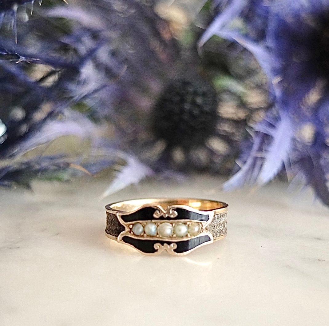 Antiker viktorianischer Ring mit weißen Saatperlen und schwarzer Emaille, gefasst in 9 Karat Gelbgold. Um das Band herum befindet sich ein geflochtenes Stück Haarwerk. Auf der Innenseite des Bandes befindet sich neben den Punzierungen die Inschrift
