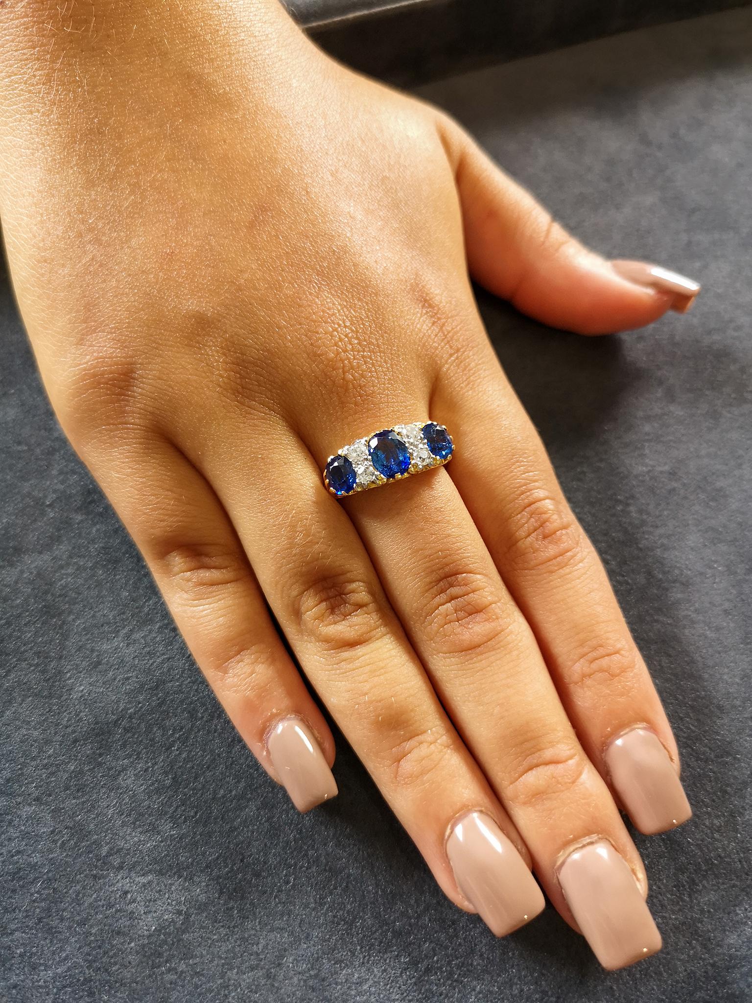 An impressive and very fine quality carved ring, circa 1890. The ornately carved 18-carat yellow gold setting mounted with three oval, inky-blue sapphires totaling approximately 3.00 carats, accented with four old-cut diamonds, mounted in platinum,