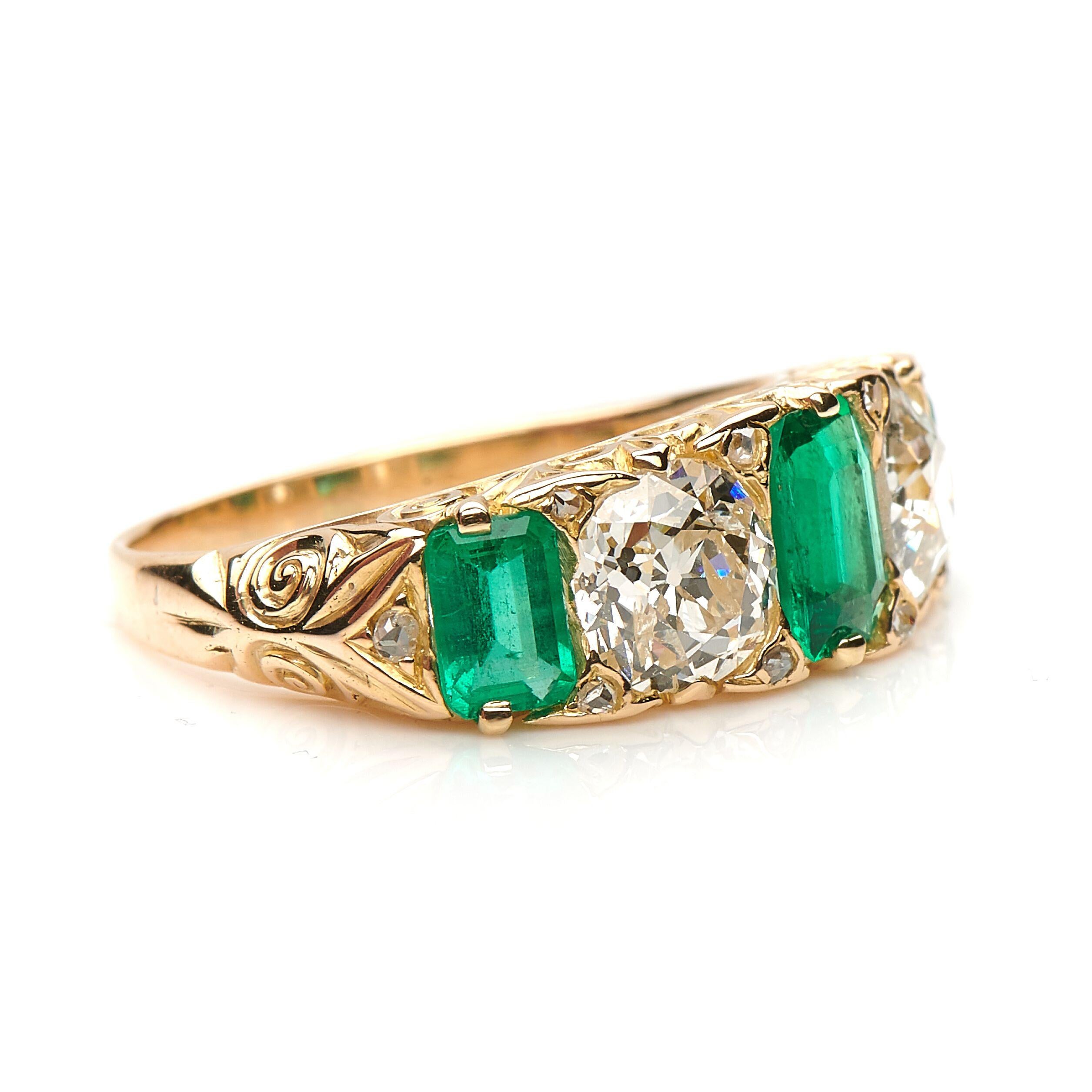 Antique emerald and diamond five stone ring, circa 1890. Horizontally set with three bright green emerald-cut emeralds interspersed with two principle old cut diamonds in a wonderfully decorative carved foliate yellow gold setting. The emeralds are