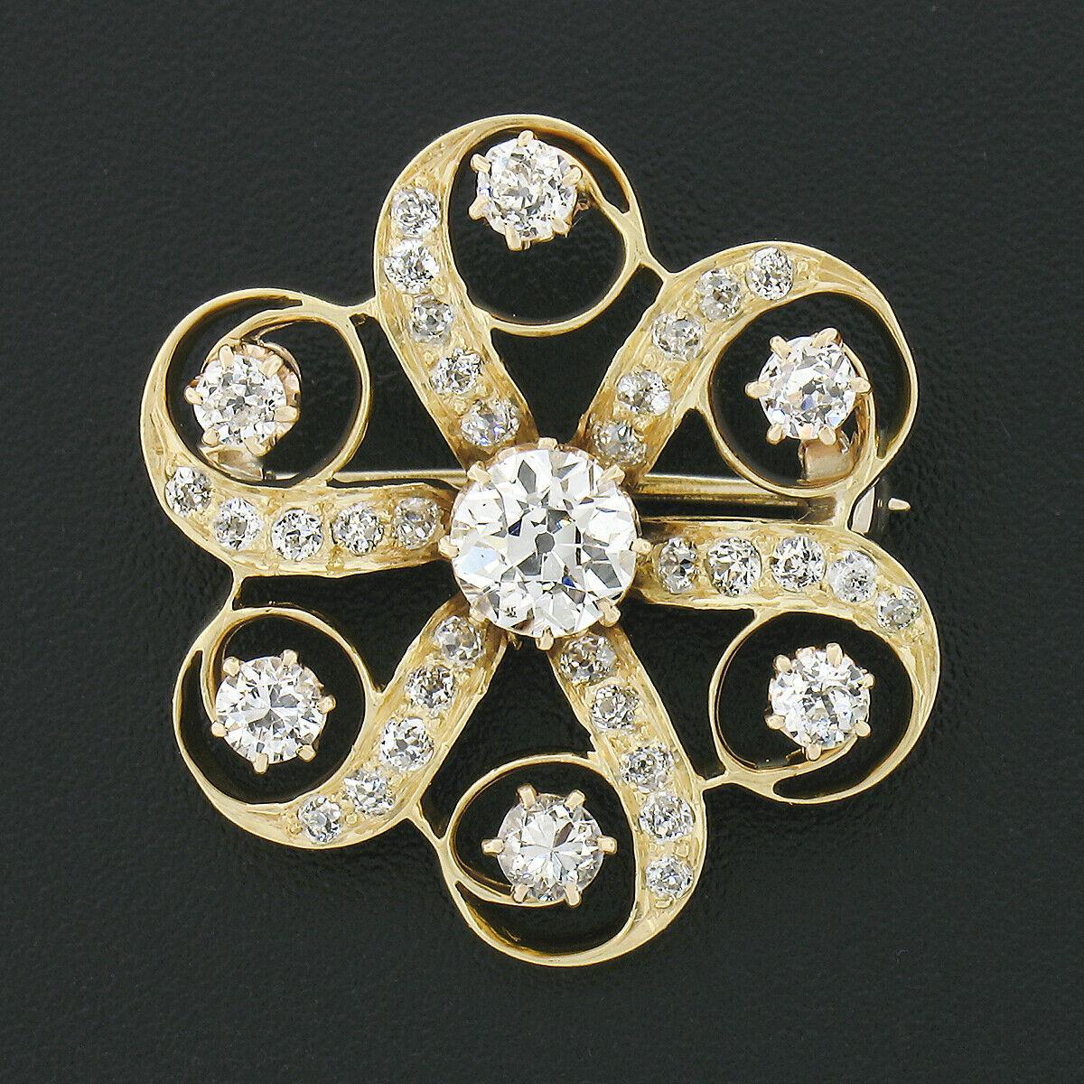 This gorgeous antique brooch pin was crafted in 18k yellow gold during the Victorian era and features an open swirl flower design that is covered in fine old European cut diamonds throughout. The center of the brooch carries a beautiful diamond that