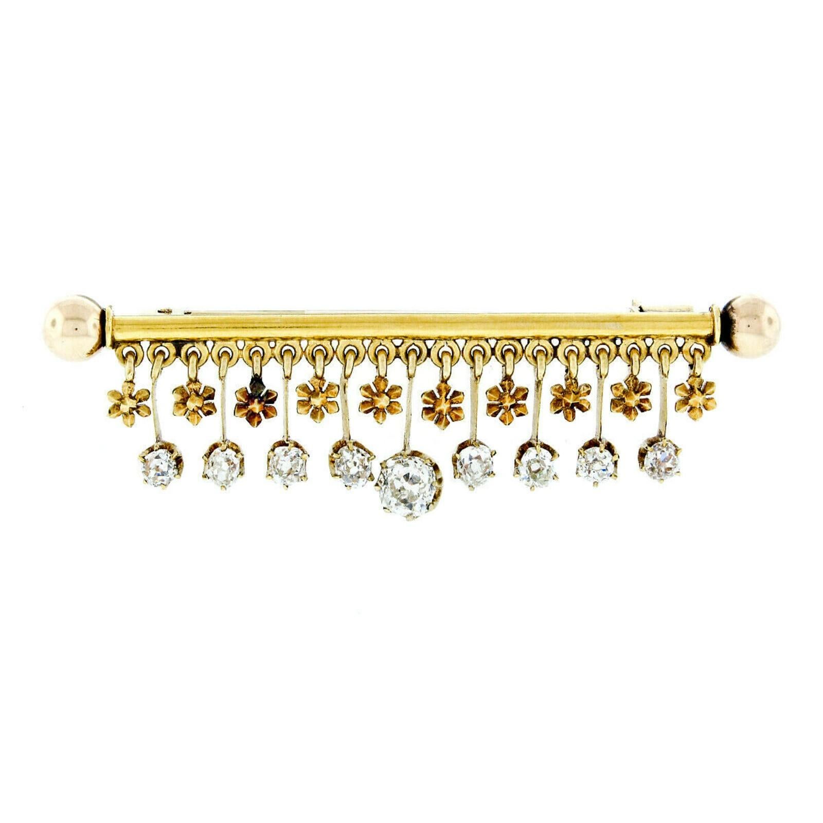 Here we have an absolutely magnificent antique dangle bar pin crafted from solid 18k yellow gold during the Victorian era. The pin features a cylindrical rod with spheres on its ends. There are then 9 old mine cut diamonds and 10 handmade six-petal