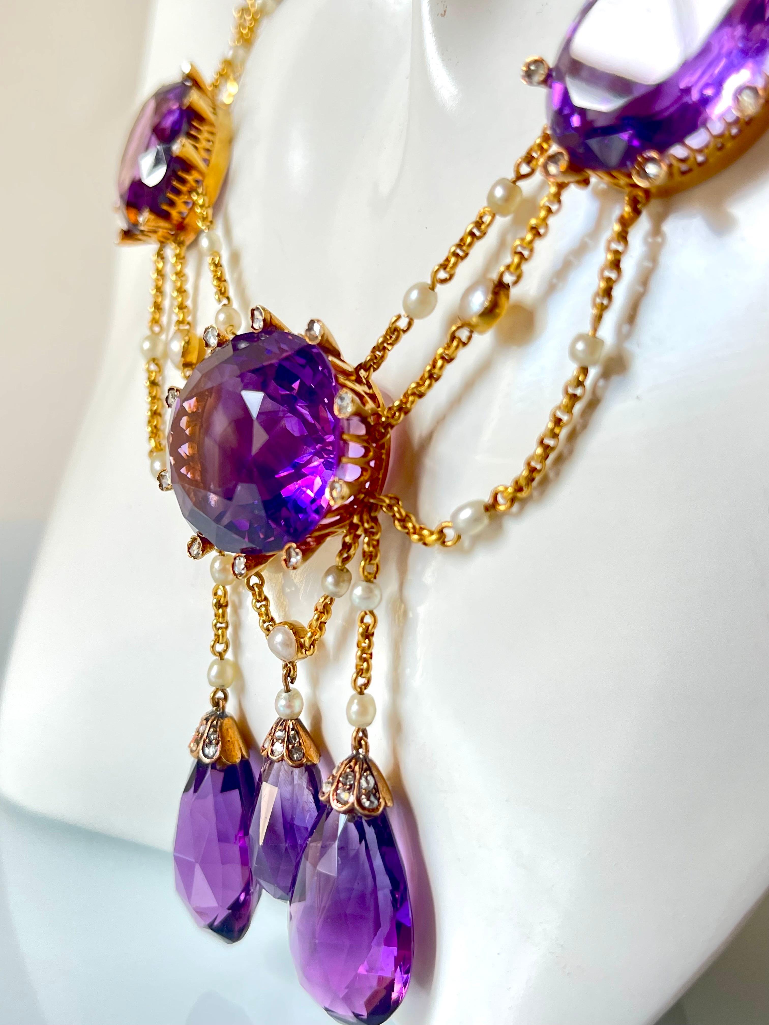 A stunning late Victorian 18K gold, amethyst, diamond and natural pearl festoon necklace composed of 
8 large oval cut, possibly Russian amethysts, totaling approximately 300ct and 3 amethyst briolettes that dangle at the center, adding movement to