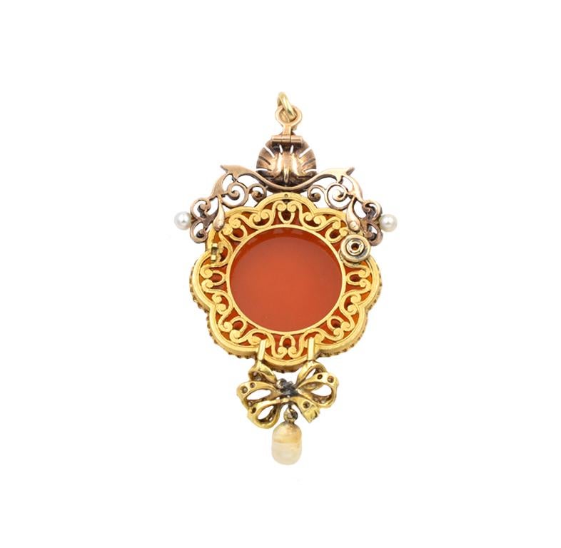 Antique Victorian carved agate cameo pendant from circa 1870s.  This beautiful 18 karat yellow gold pendant features a hardstone cameo in carnelian and white agate pendant with a carved depiction of a woman with lyre.  The cameo is surrounded by 16