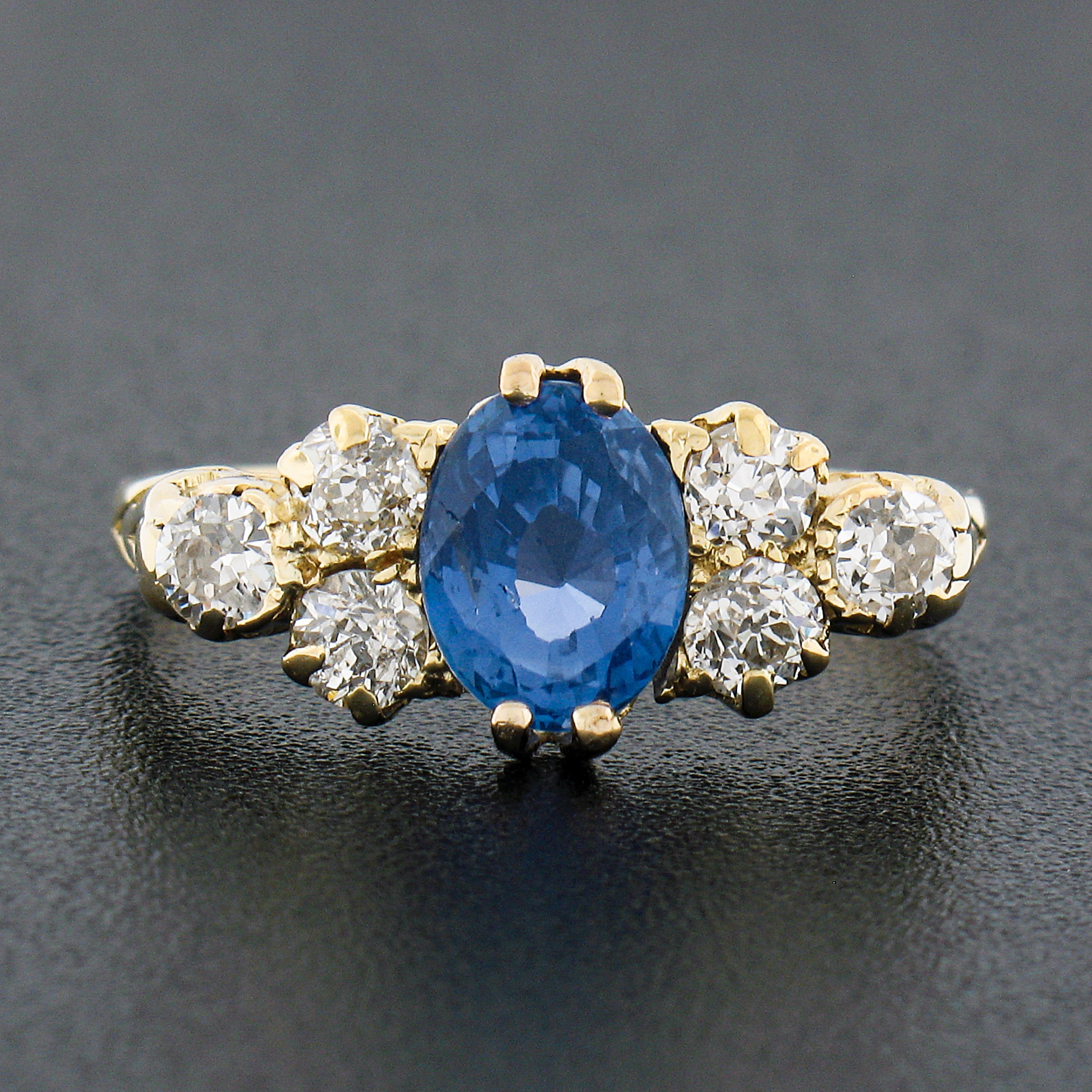 Here we have an absolutely gorgeous antique band ring crafted in solid 18k yellow gold during the Victorian period. The ring features an approximately 1.75 carat, oval cut, natural Burma sapphire at its center and flanked on either side by a fiery
