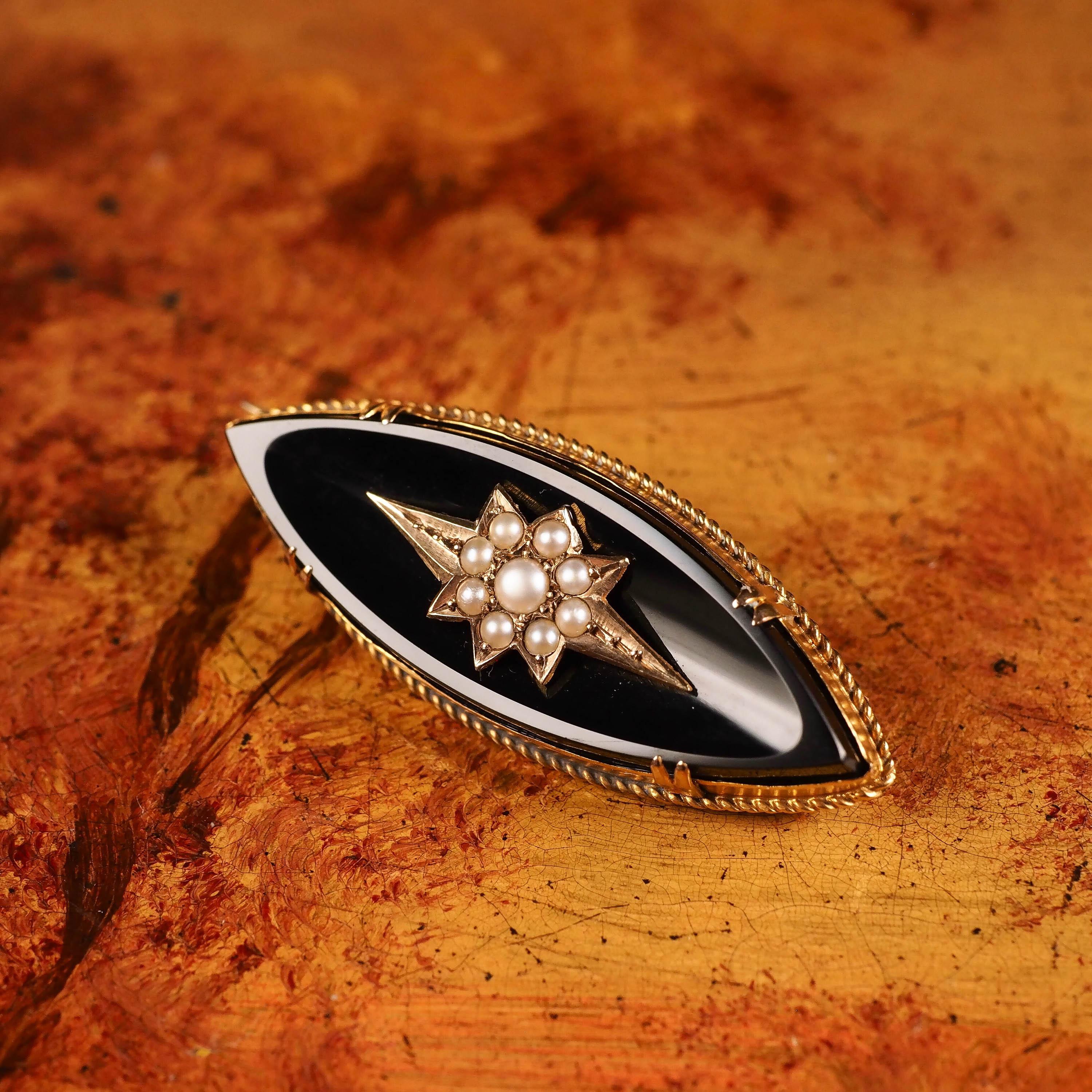 We are delighted to offer this stylish antique Victorian 18K gold brooch. The brooch features a large marquise-shaped onyx with 18K gold mounting.

The central portion presents a fabulous star-shaped gold cartouche with 9 seed pearls intricately set
