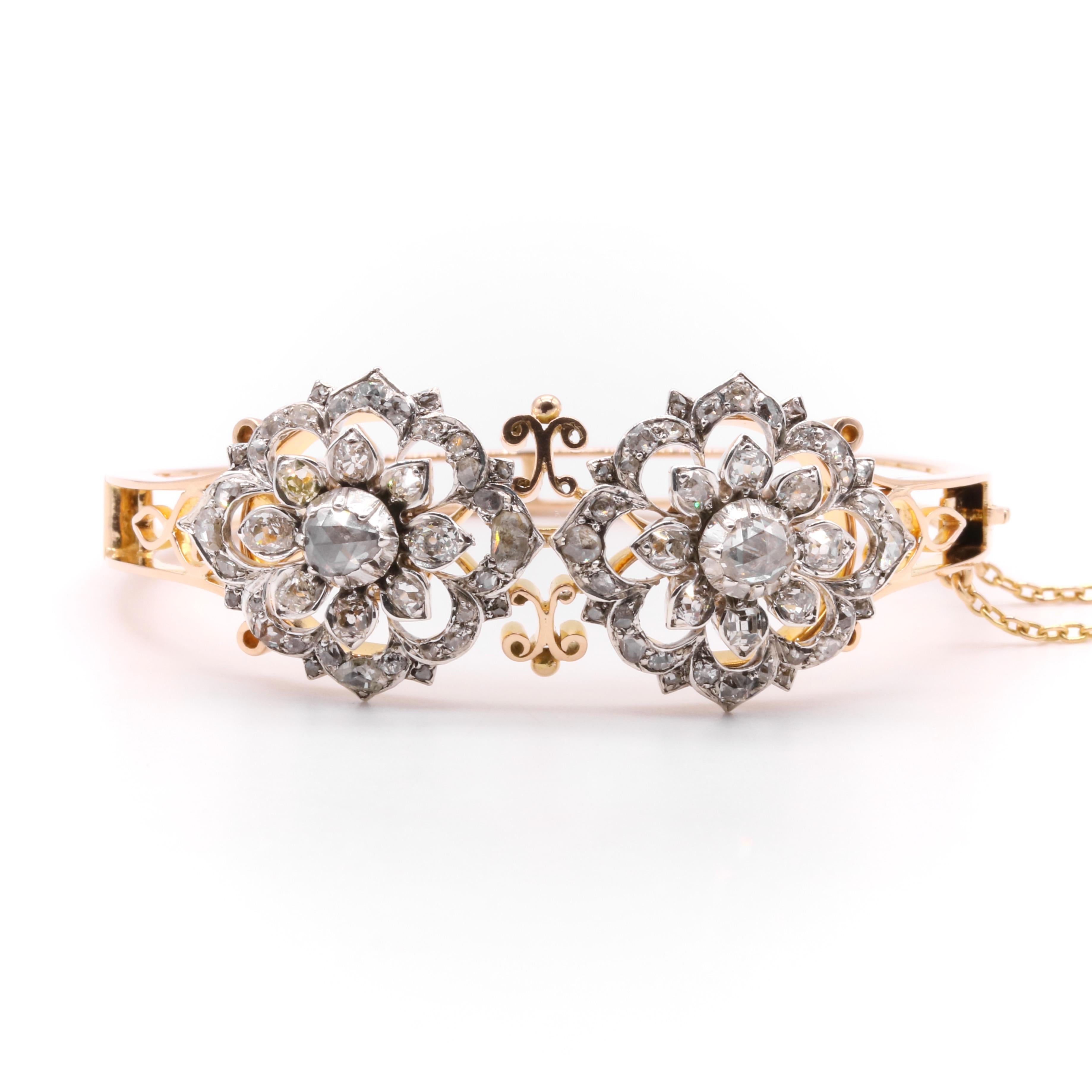 A Victorian diamond, silver, and yellow gold bangle, comprising two detachable brooch fittings each comprising one large rose cut diamond, and forty old mine cut and rose cut diamonds, set in silver, with an 18 karat yellow gold bangle, and 9 karat