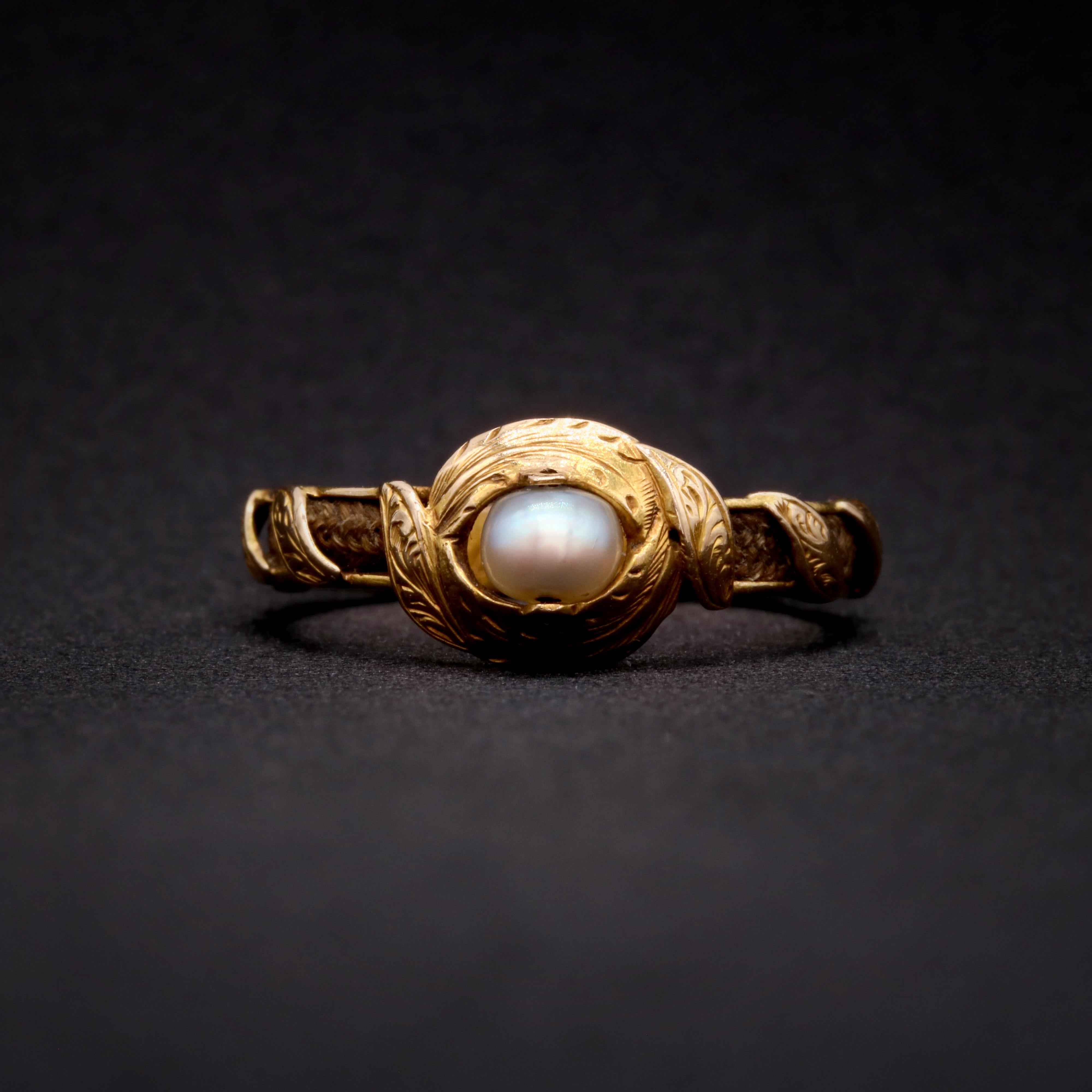 A Victorian pearl, hairwork, and yellow gold ring, comprising one pearl, set in 18 karat yellow gold, with panels of plaited hairwork. 

This curious mourning ring is unlike any other that I have come across before. The ring centres on a shimmering