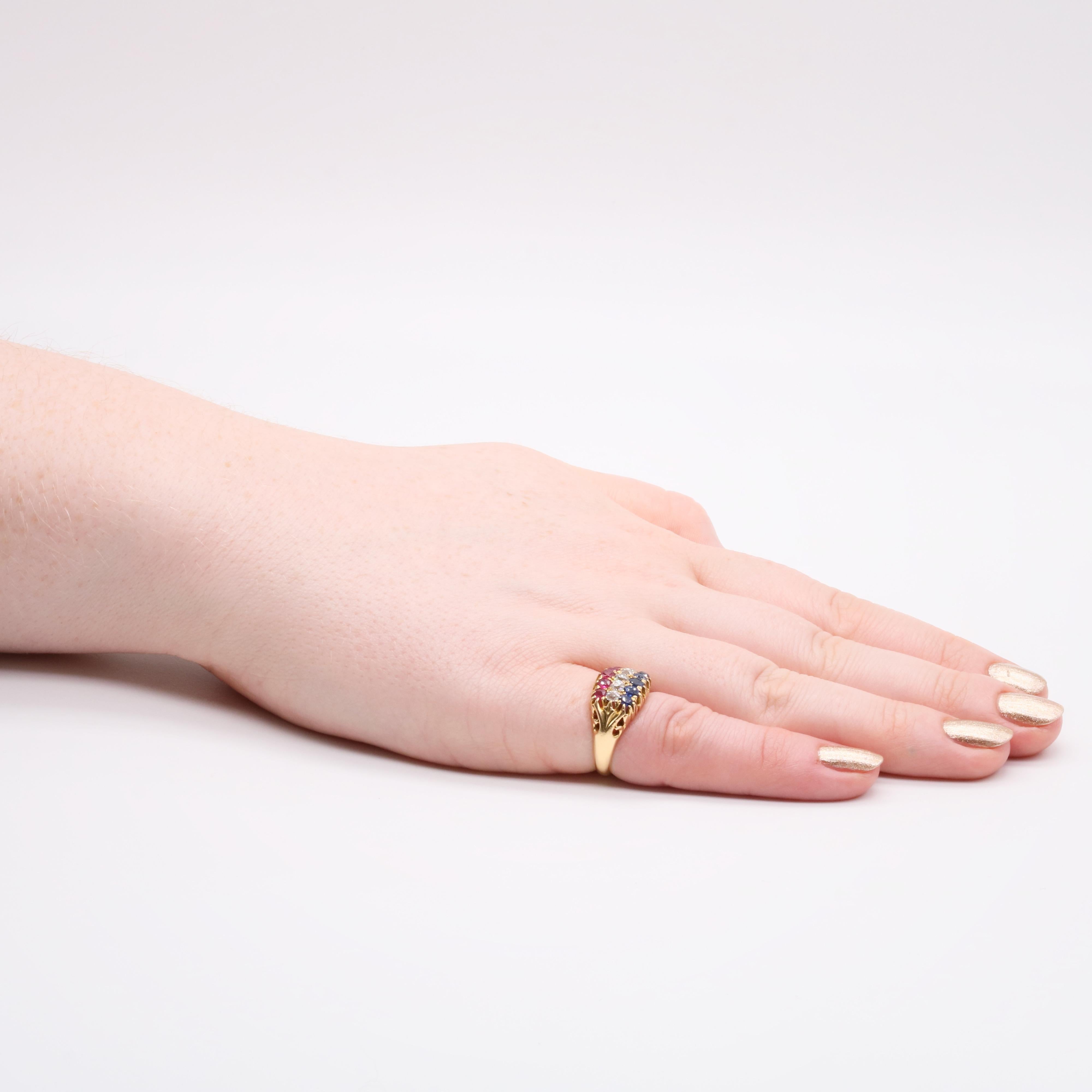 A yellow gold, sapphire, diamond and ruby ring, comprising five cushion shaped sapphires, five old mine cut diamonds and five cushion shaped rubies, set in 18 karat yellow gold, to a band of 18 karat yellow gold. 

Three rows of sparkling gemstones