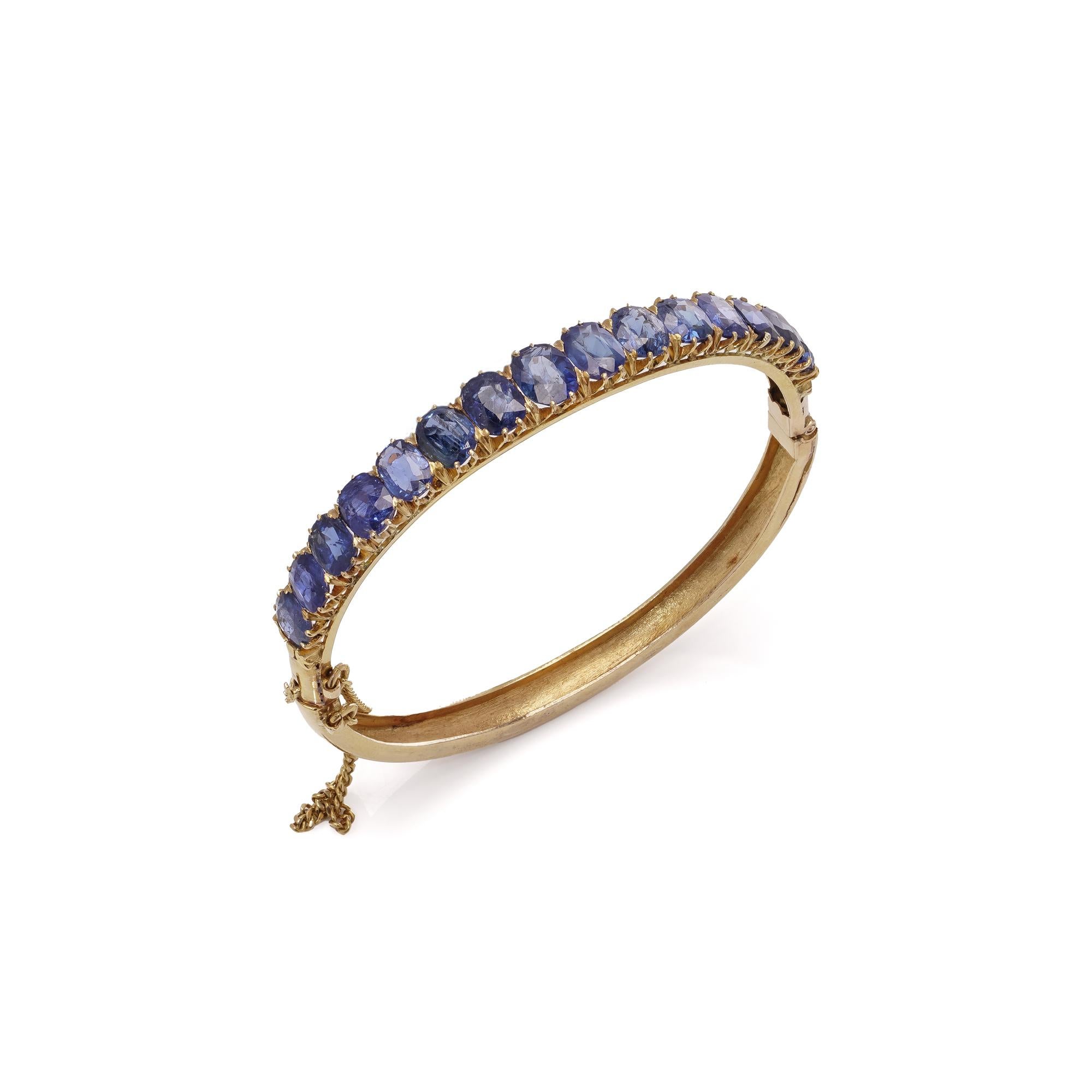 Antique Victorian 18kt gold Sapphire bangle with safety chain.

This beautiful bangle is made from the early Edwardian period, crafted in 18kt gold.
The design showcases a row of deep blue, oval-cut sapphires set in a claw setting along the