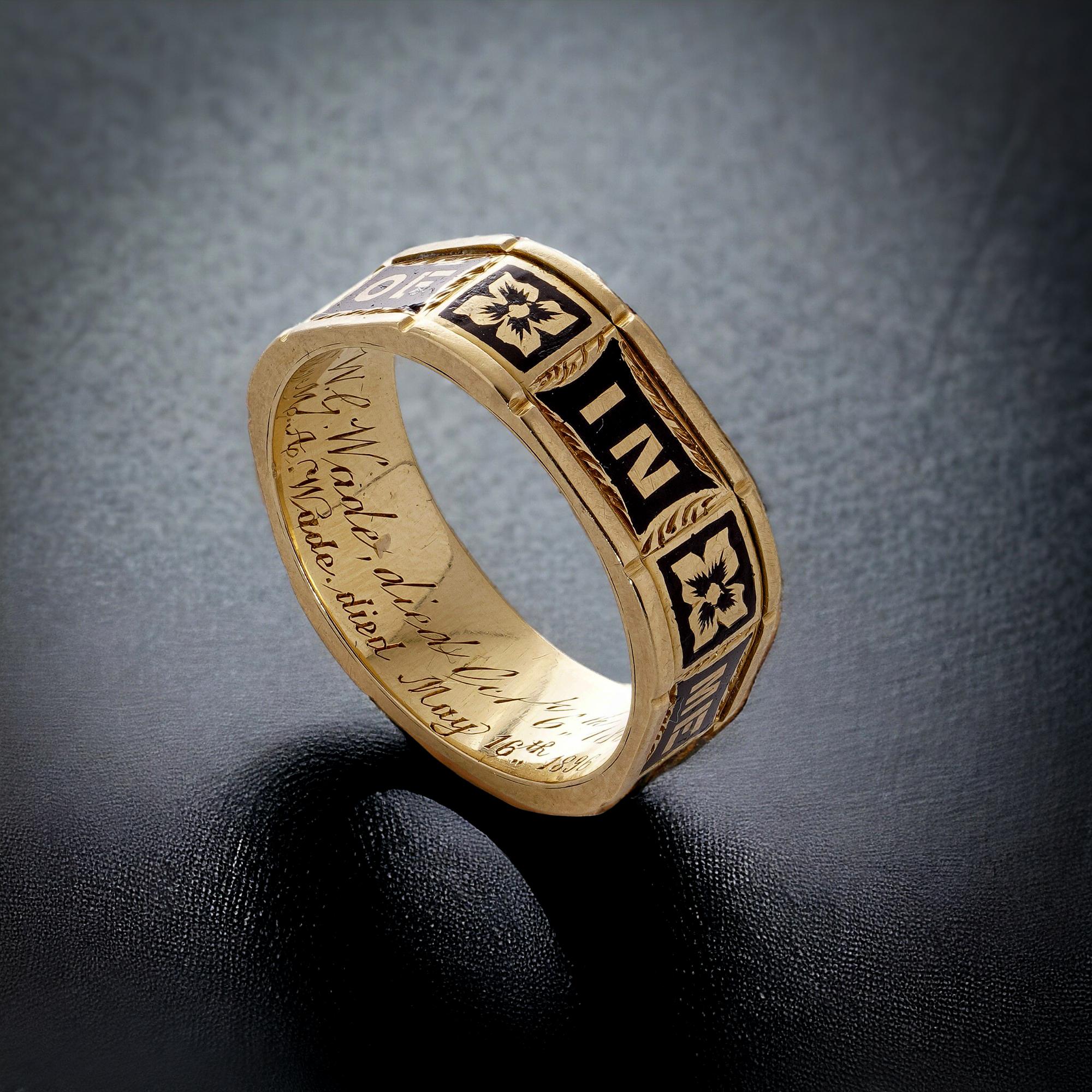 This mourning ring is an antique Victorian piece crafted from 18kt yellow gold, featuring intricate black enamel detailing. Encircling the band are the words 