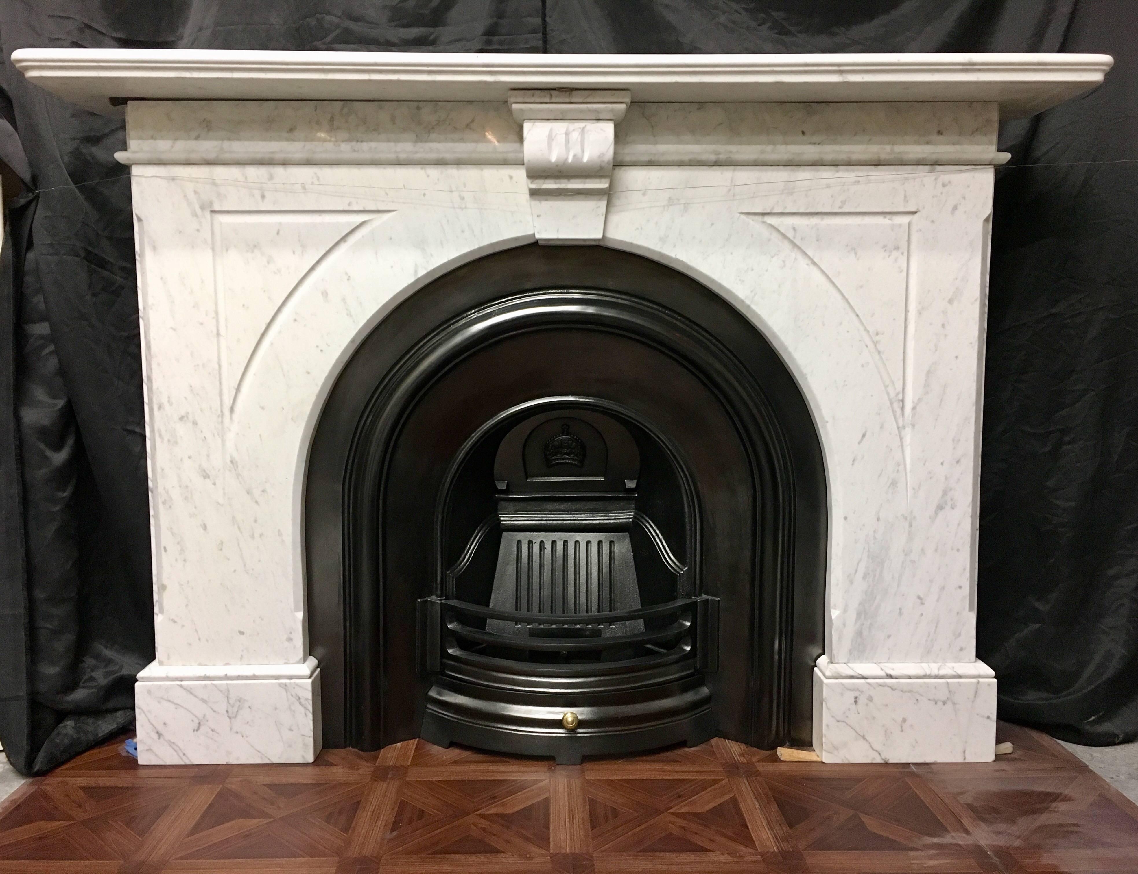 A classic antique Victorian 19th century arched spandrel fireplace surround in white Carrara marble, a moulded shelf sits above a large pair of carved spandrels, connected by a central carved stylised keystone with top capping, spandrels terminate