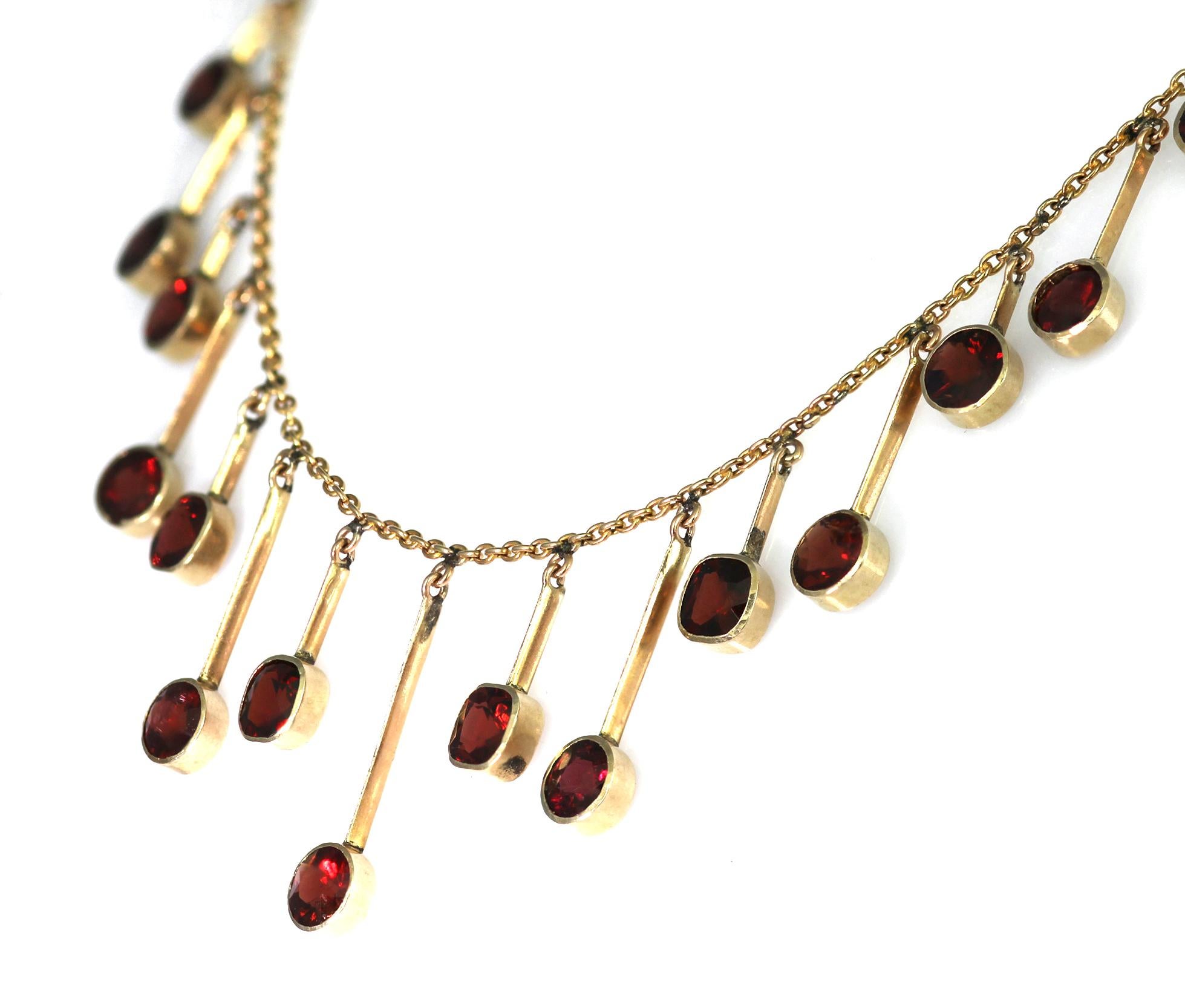 Antique timeless classic necklace, a Late 19th century 9 carat yellow gold and garnet fringe necklace. The necklace itself consists of a yellow gold chain with metal bars dangling off the chain each with a stunning garnet attached to it. The clasp