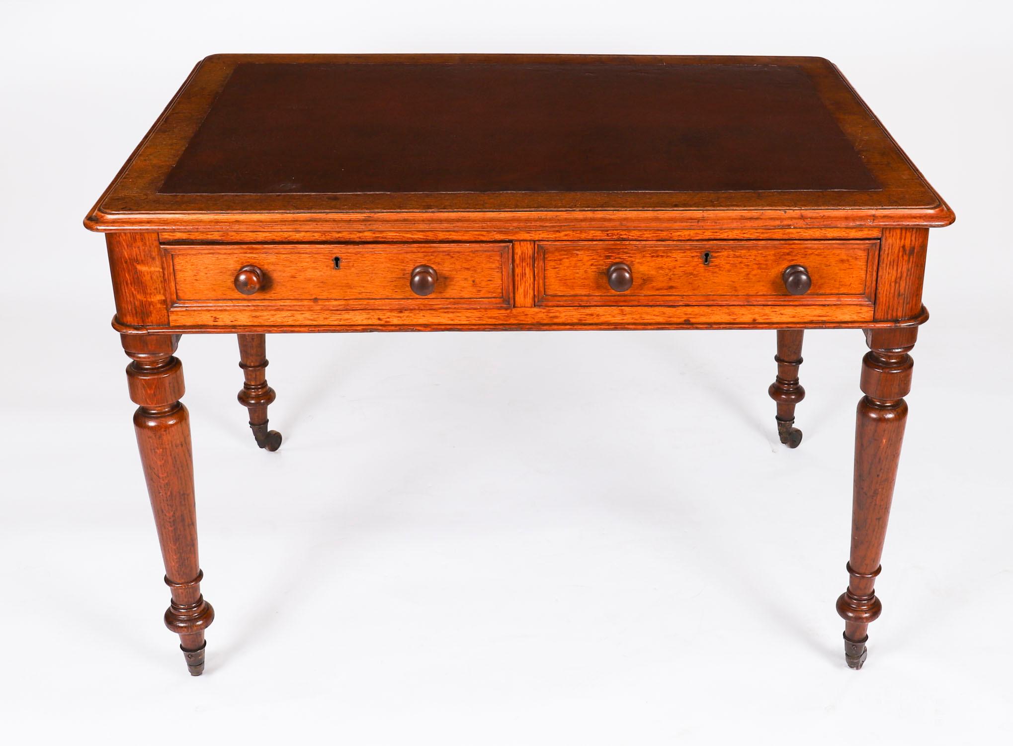 Cette magnifique table à écrire antique du début de l'époque victorienne est fabriquée en chêne massif et date d'environ 1860.
 
Le plateau rectangulaire aux angles arrondis est équipé d'un écritoire en cuir brun d'origine. Il comporte deux tiroirs