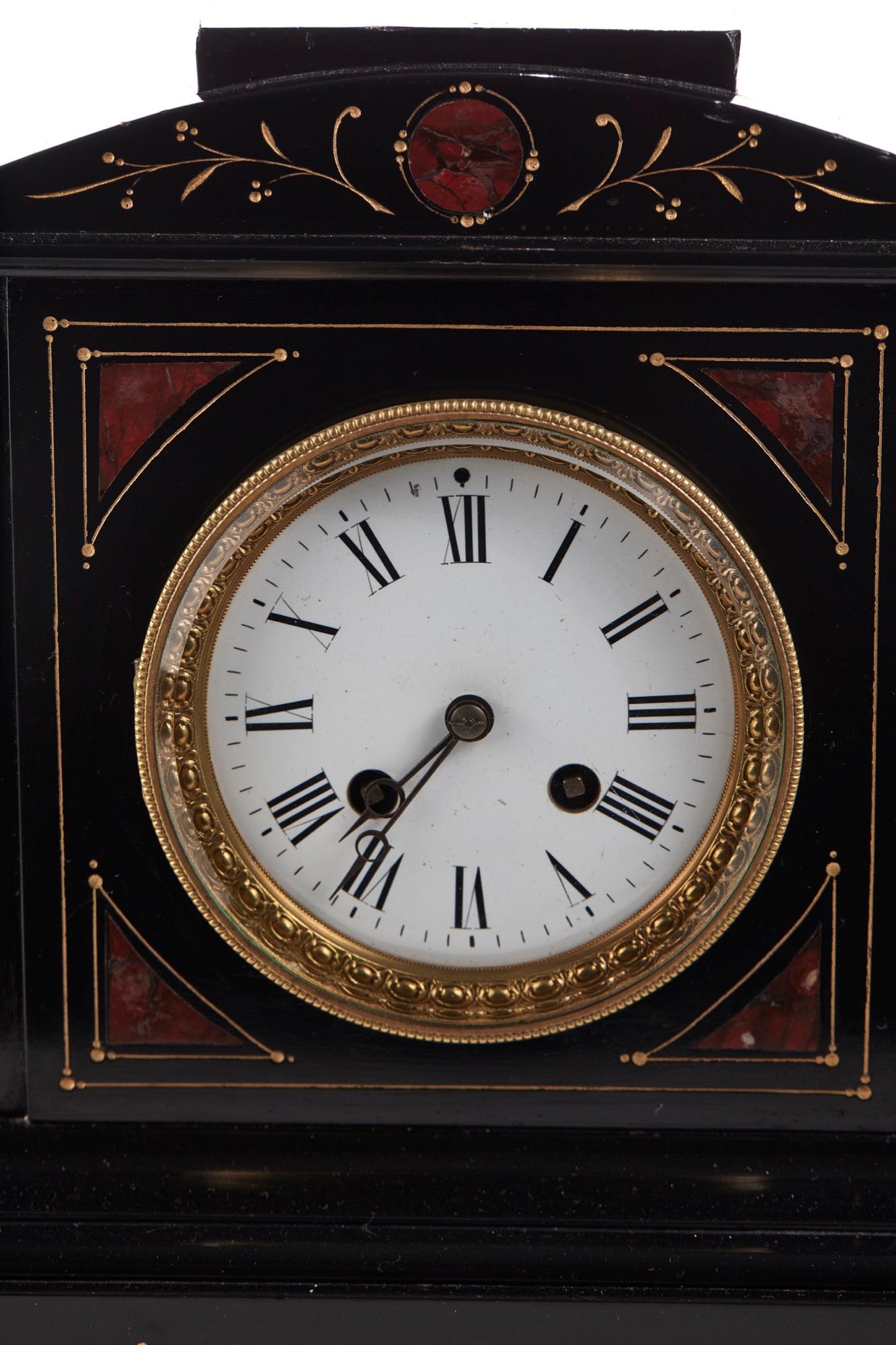 This is a 19th century Victorian antique 8 day marble mantel clock in a lovely shaped black, red and gold case with enameled dial, brass bezel and 8 day movement striking on a bell. It has an original key.