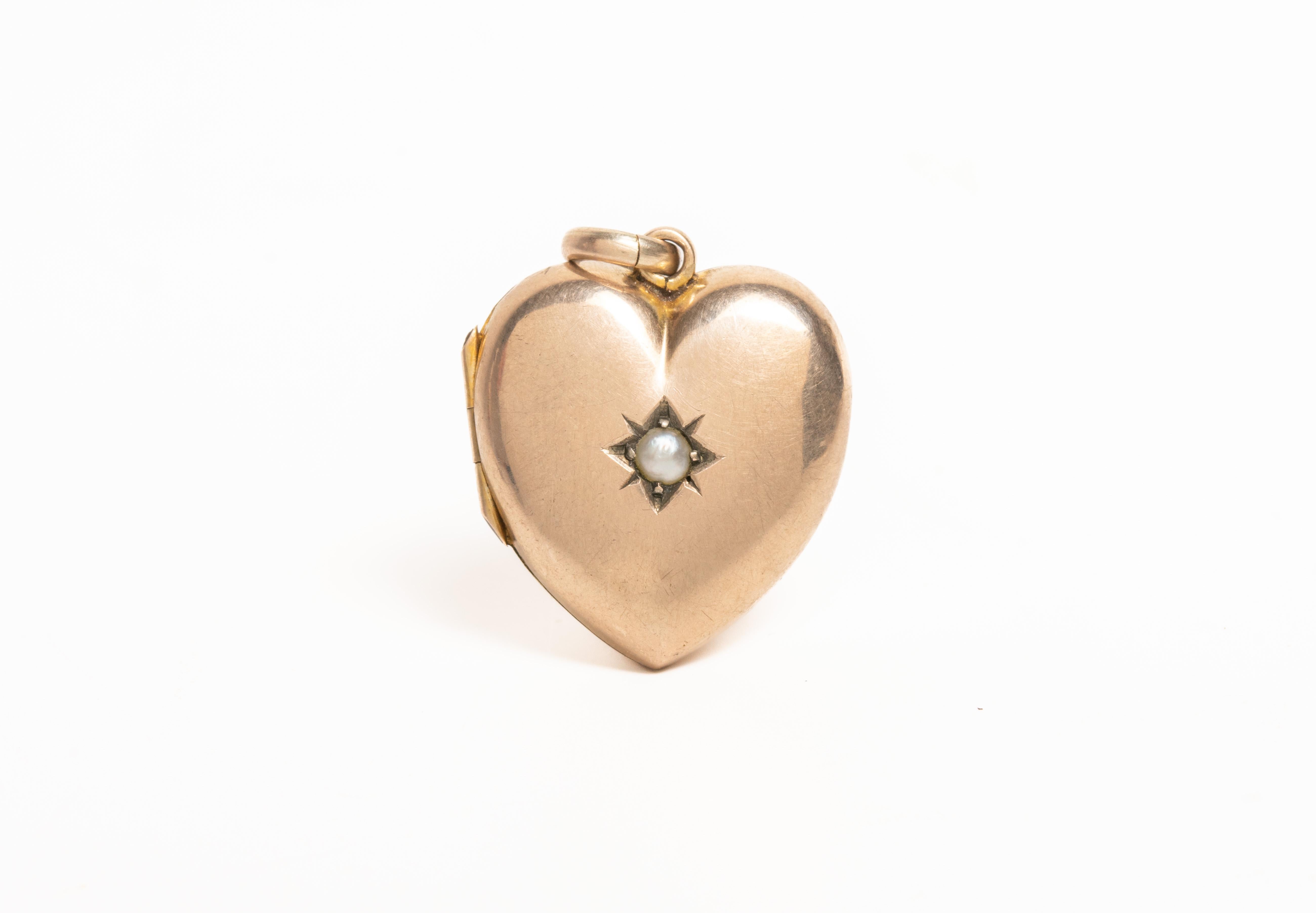 Dieses charmante antike viktorianische Herz Perle Medaillon ist in 9ct Gelbgold gefertigt. Das Medaillon ist mit einem Sternmotiv verziert, in dessen Zentrum ein Perlenstein liegt. Das Medaillon lässt sich öffnen und gibt den Blick auf zwei Fächer