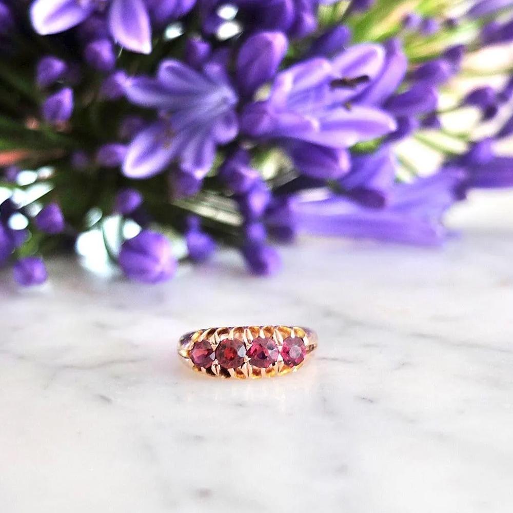 Questo bellissimo anello vittoriano presenta una fila di quattro granati dal taglio rotondo e ricco, i cui toni rossi profondi risplendono in una montatura in oro rosa 9ct. Ogni gemma è incastonata in una galleria decorativa intagliata - un design