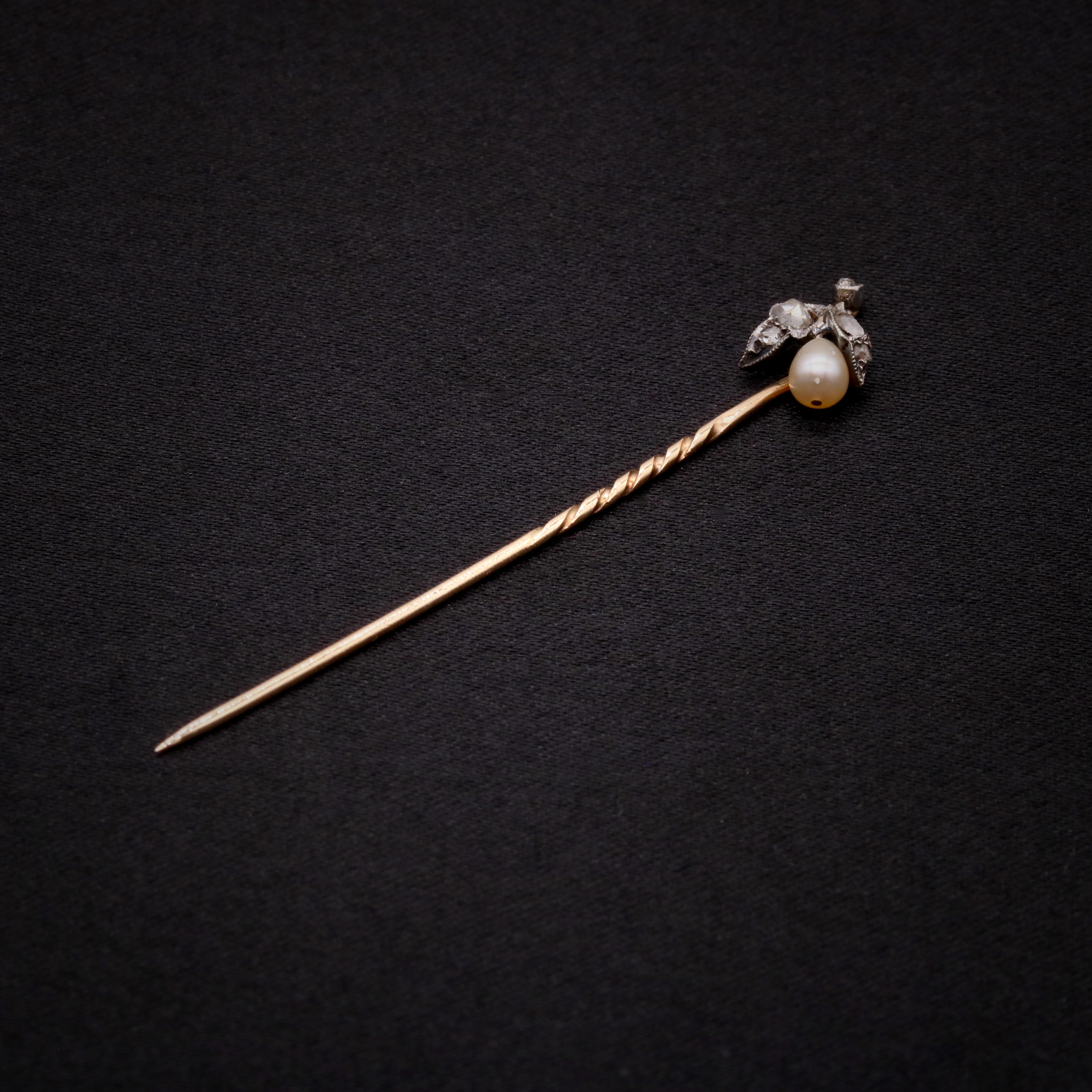 A Victorian pearl, diamond, silver and yellow gold stick pin, comprising one pear shaped pearl, and five rose cut diamonds, set in silver, with a 9 karat yellow gold pin and back. 

This elegant stick pin is designed as a fruit or the bud of a