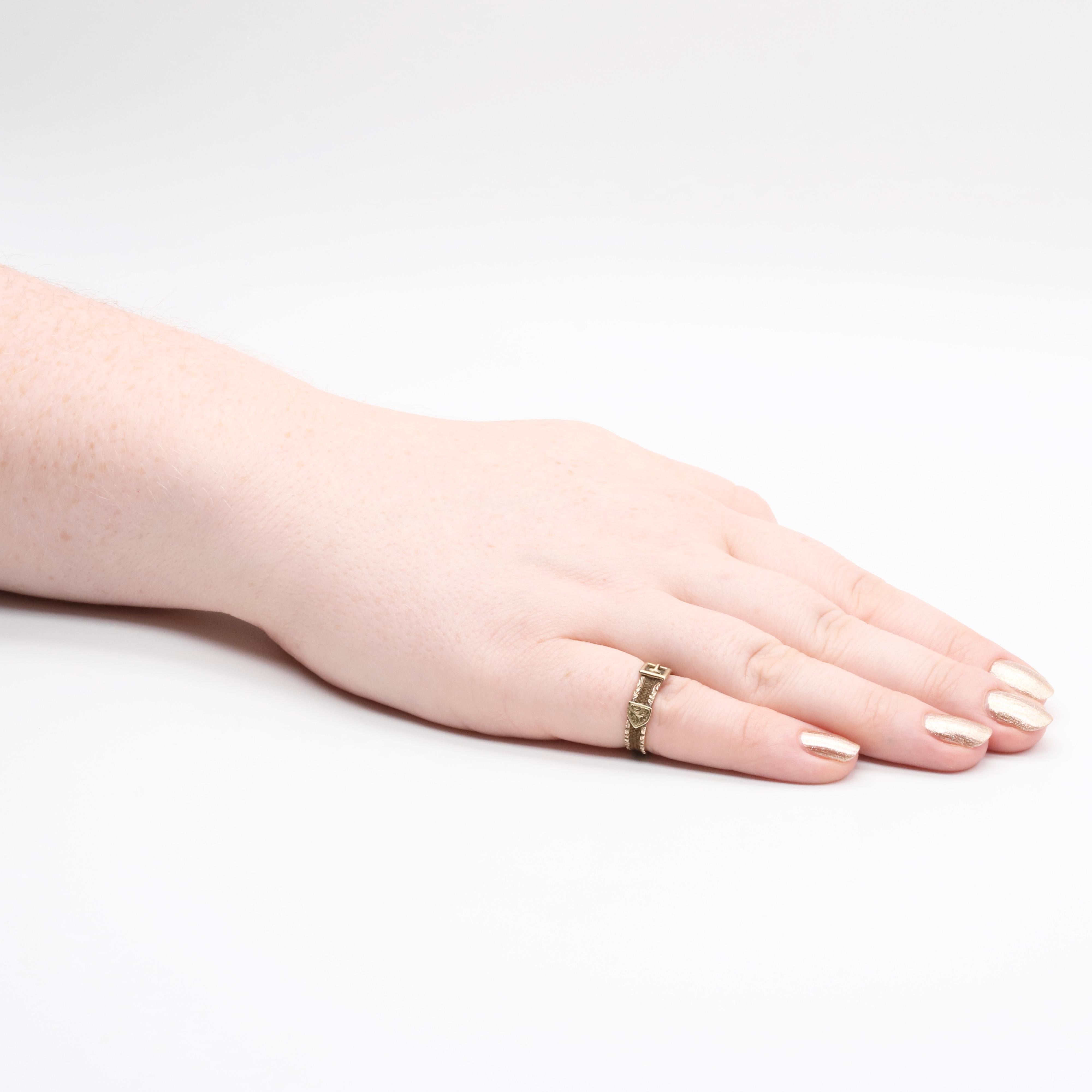 An antique hairwork and gold ring, comprising plaited brunette hairwork, set in a 9 karat yellow gold band. 

This unusual ring is crafted in the form of a buckle, or belt. The edge of the buckle is carved with floral details, all the way around and