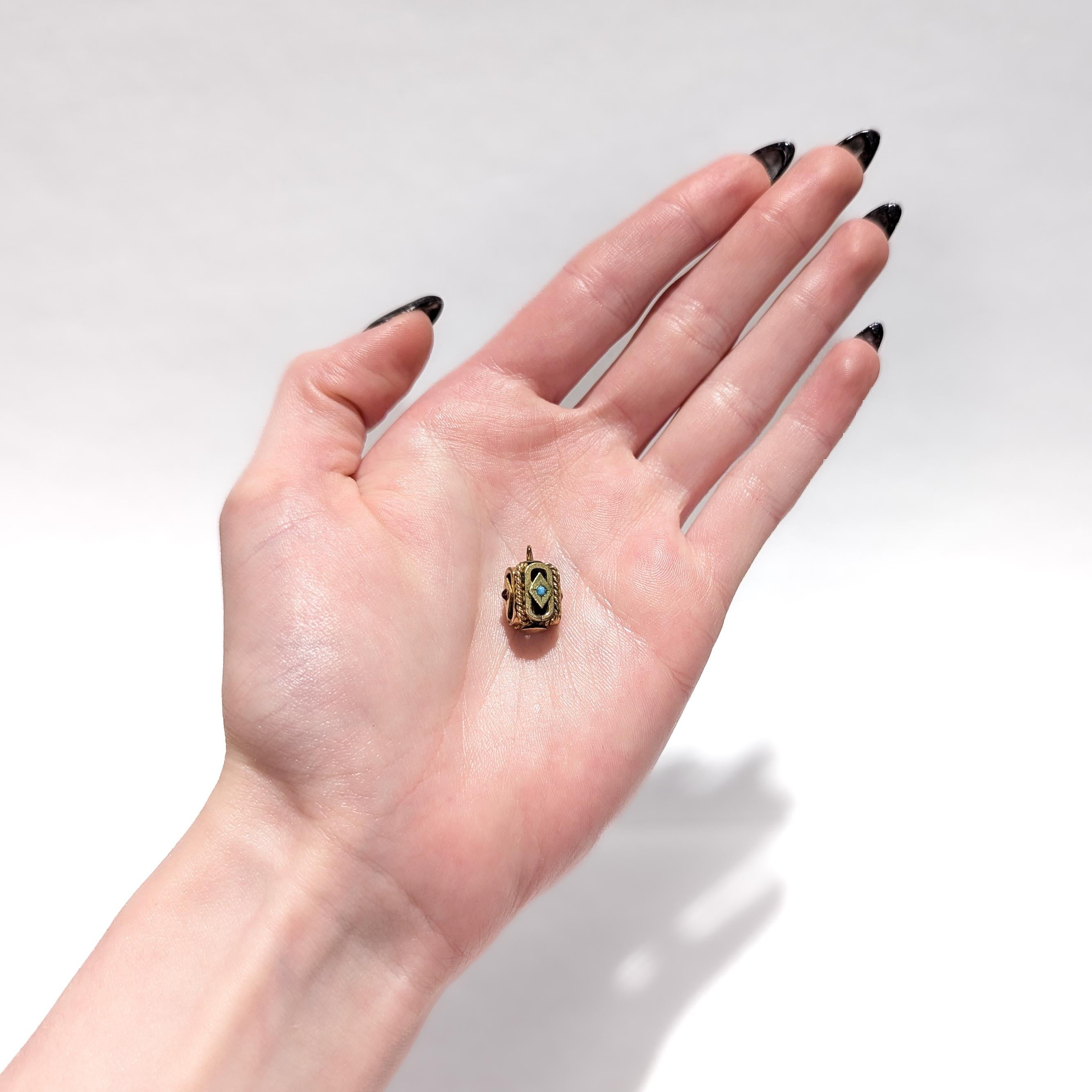 A fine antique gold-filled Aesthetic Movement charm.

With a gold-filled body in a rectangular shape

Bezel-set to its sides with alternating turquoise and red colored glass cabochons in diamond-shaped cartouches on lozenge formed sides offset by